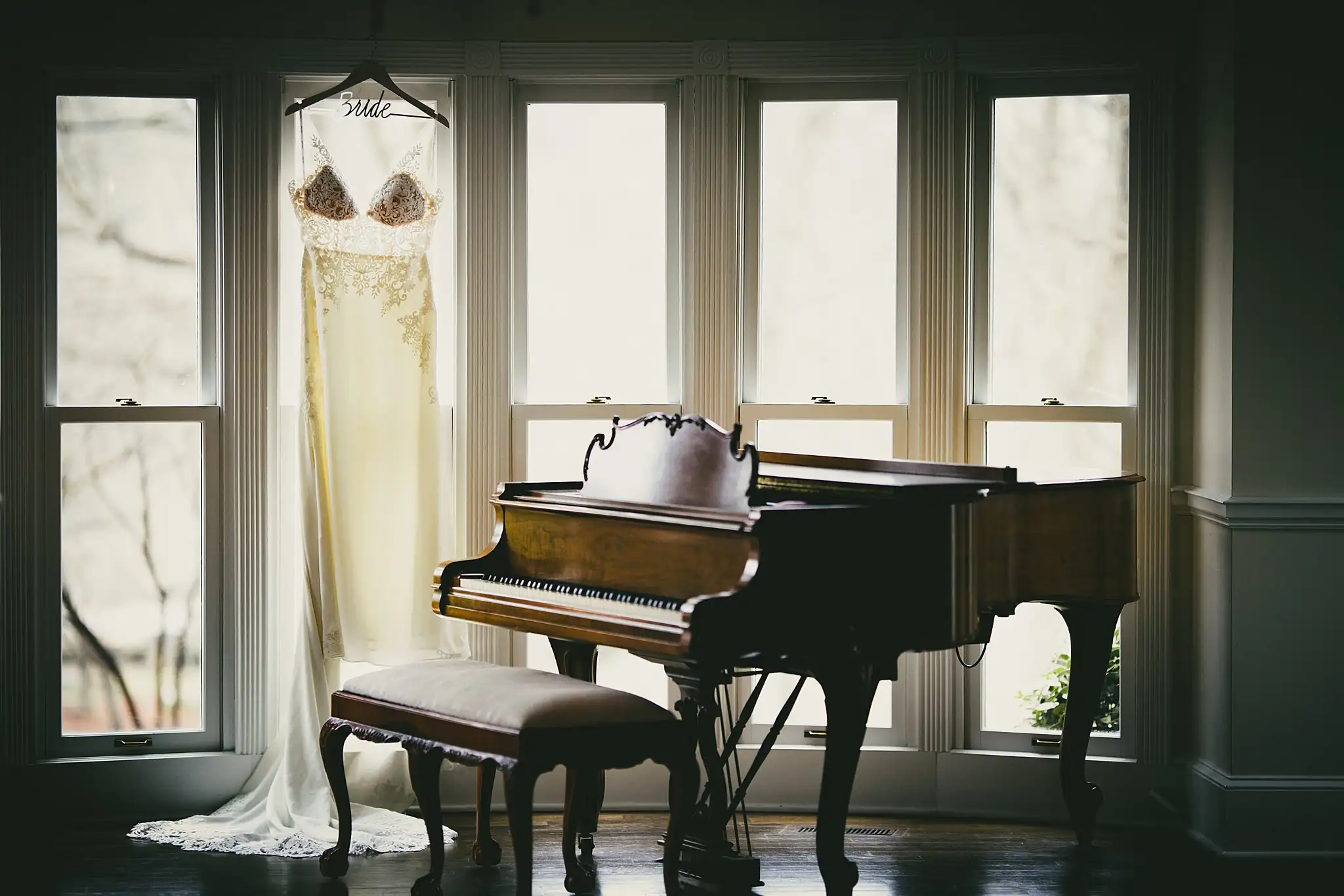 2019-04-22_0005.jpg Wedding Details: the gown hanging by the grand piano in the bay window, at a wedding at Little River Farms in Milton, GA