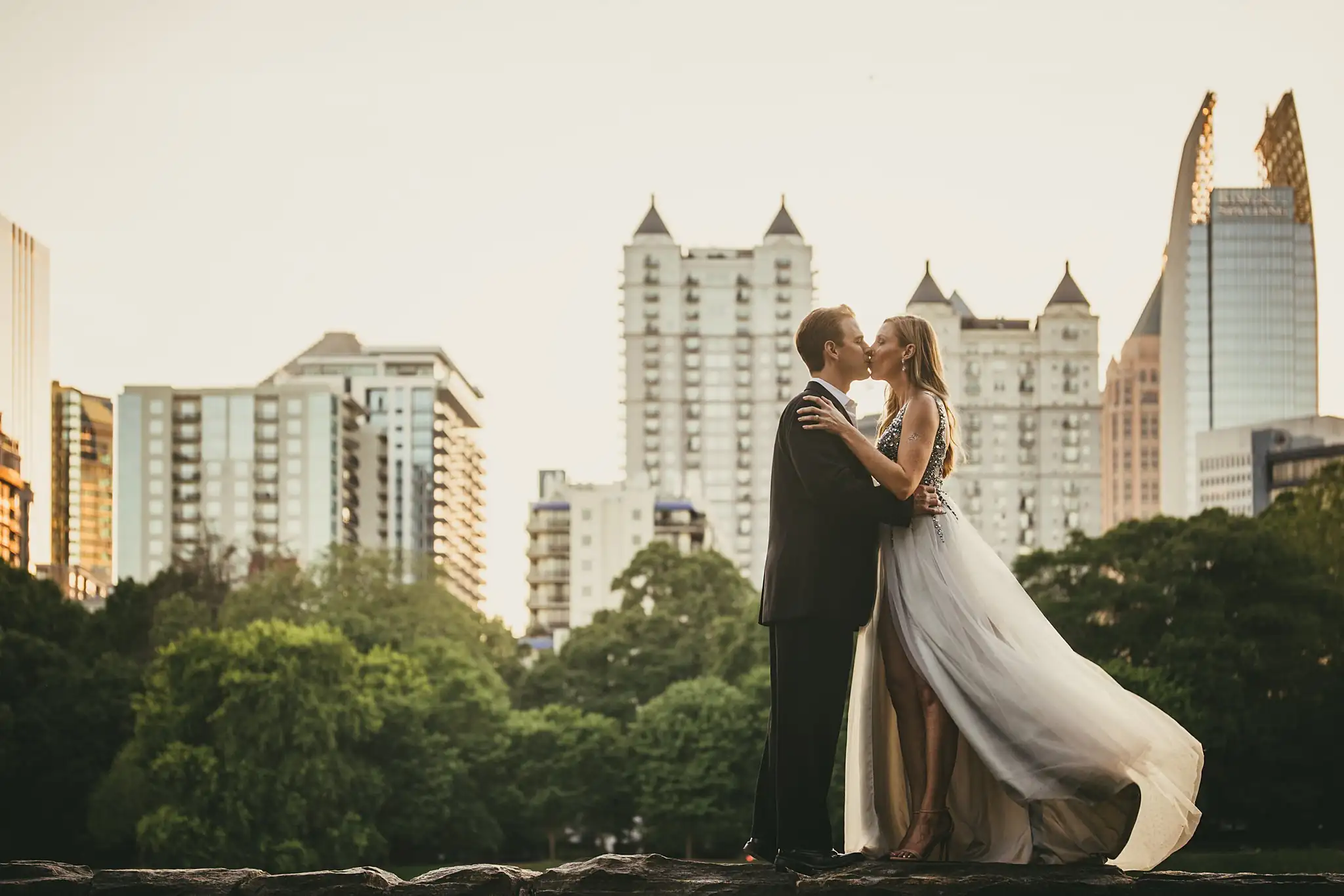 AtlantaWeddingPhotographers_0357.jpg Engagement Portraits: a kiss on the wall with her skirt flying out, during their engagement session in Midtown Atlanta, GA