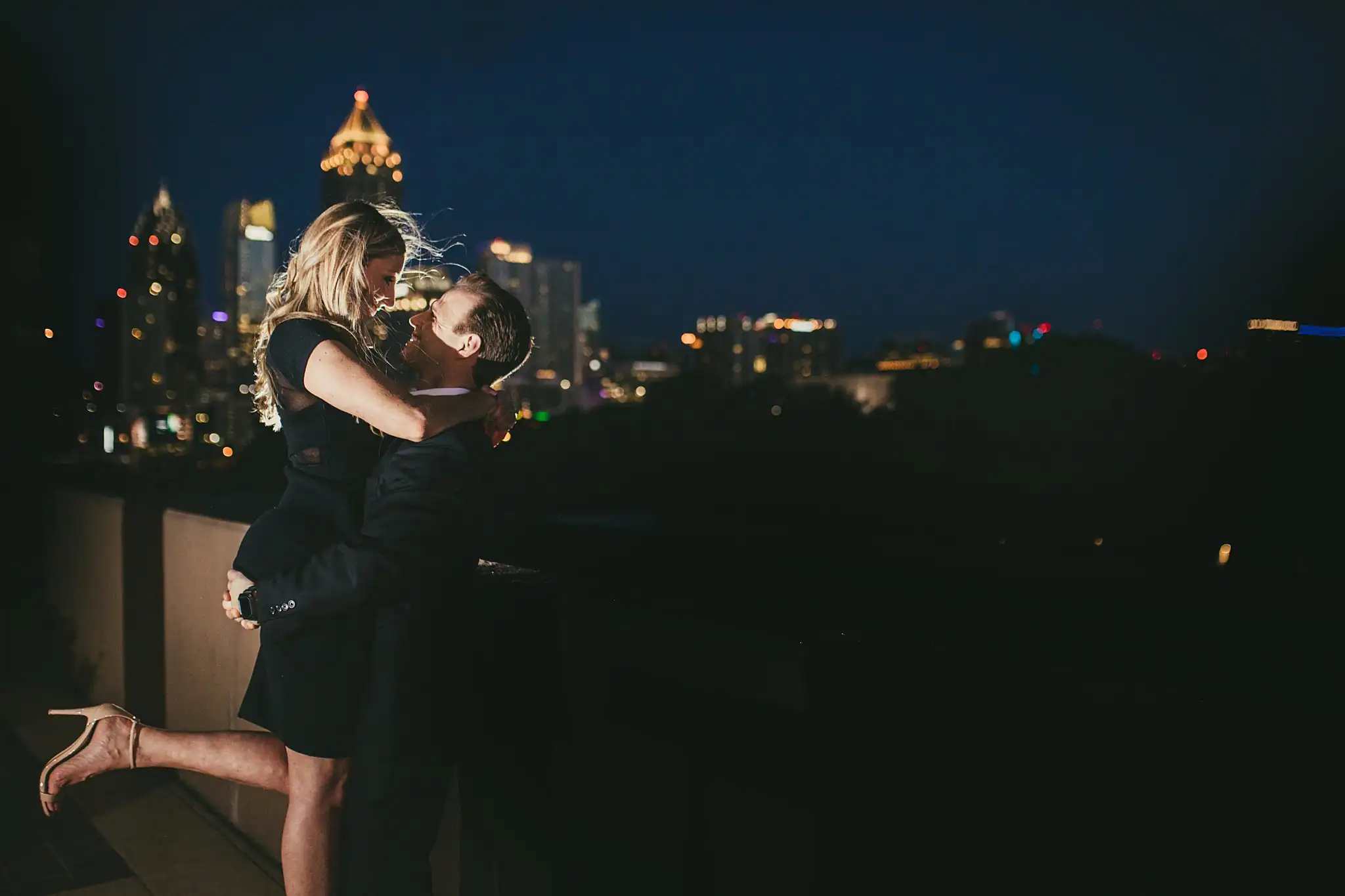 AtlantaWeddingPhotographers_0360.jpg Engagement Portraits: her jumping into his arms with the skyline behind, during their engagement session in Midtown Atlanta, GA
