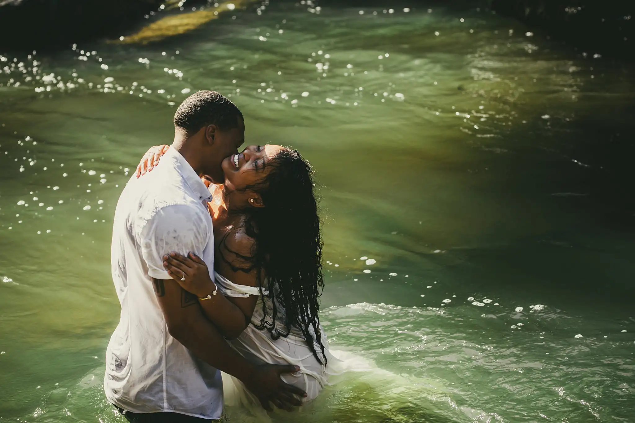 Vickery Falls at Roswell Mill Adventure Engagement Session Atlanta Wedding Photographers Engagement Portraits: a kiss waist-deep in the green water, during their engagement session at the Roswell Mill in Roswell, GA