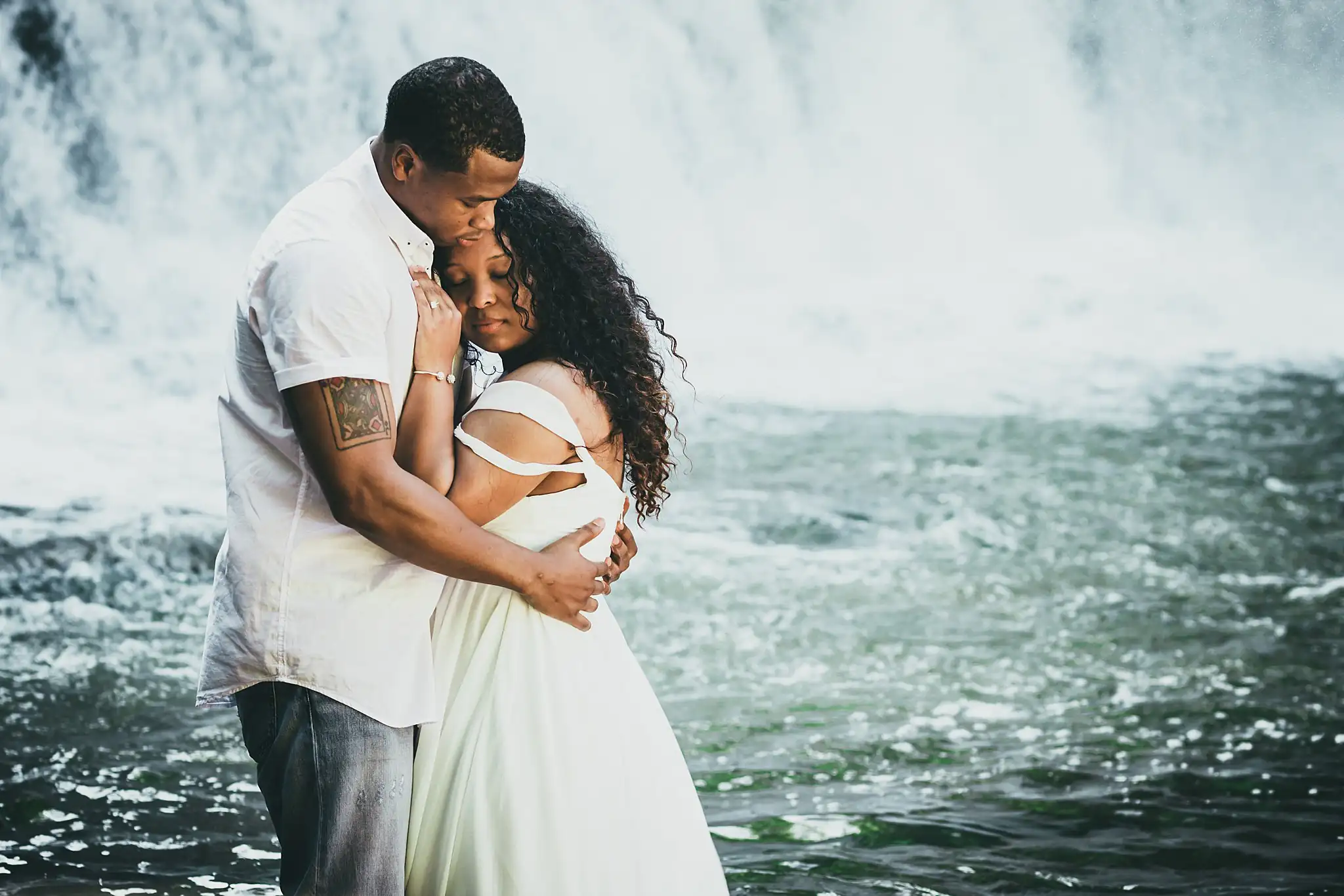 Engagement Portraits: the two of them holding each other in the spray, during their engagement session at the Roswell Mill in Roswell, GA