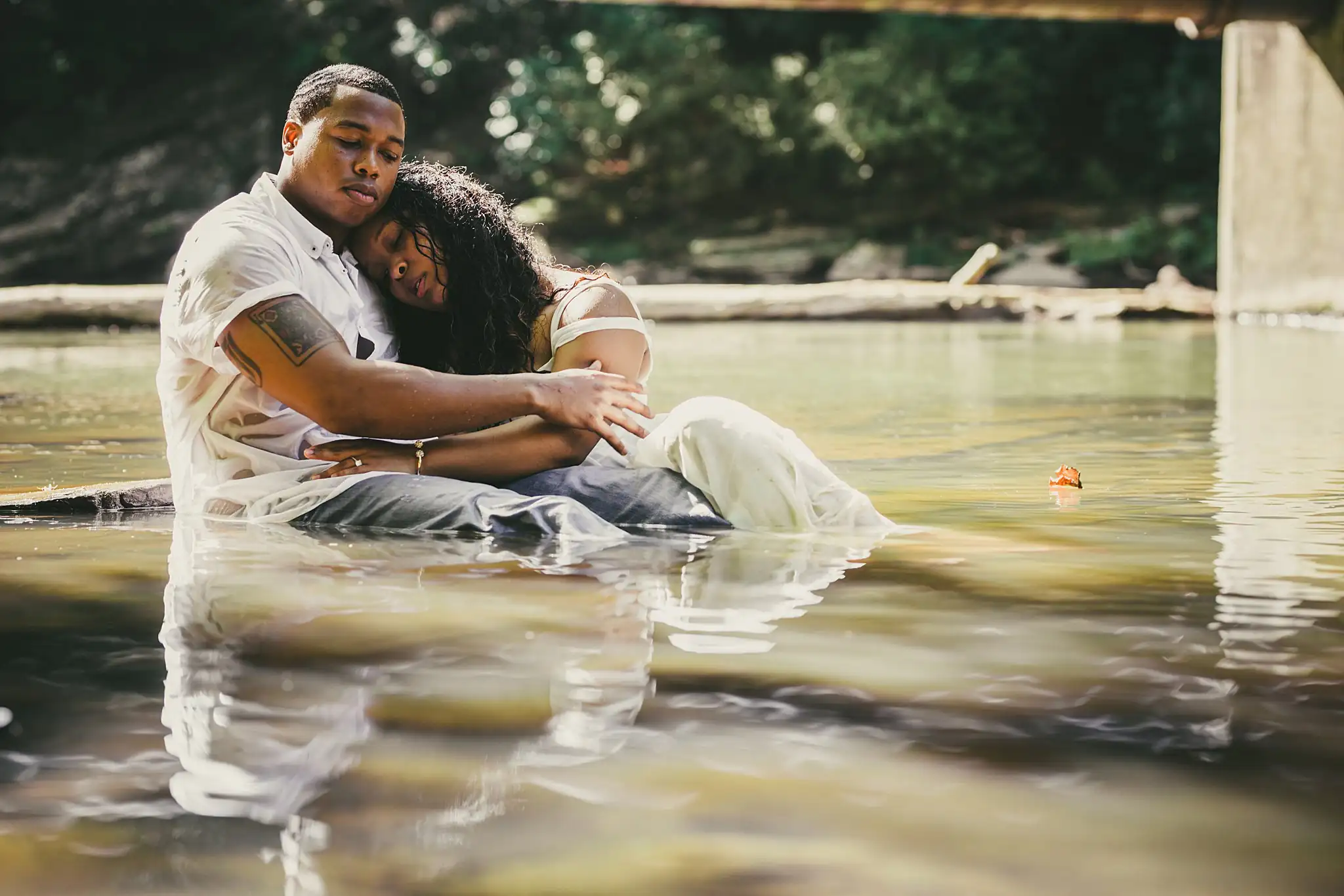 Engagement Portraits: the couple sitting together in the shallows, during their engagement session at the Roswell Mill in Roswell, GA
