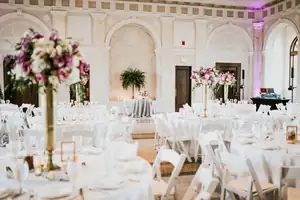 Reception Details: a white columned ballroom lit purple, at a wedding