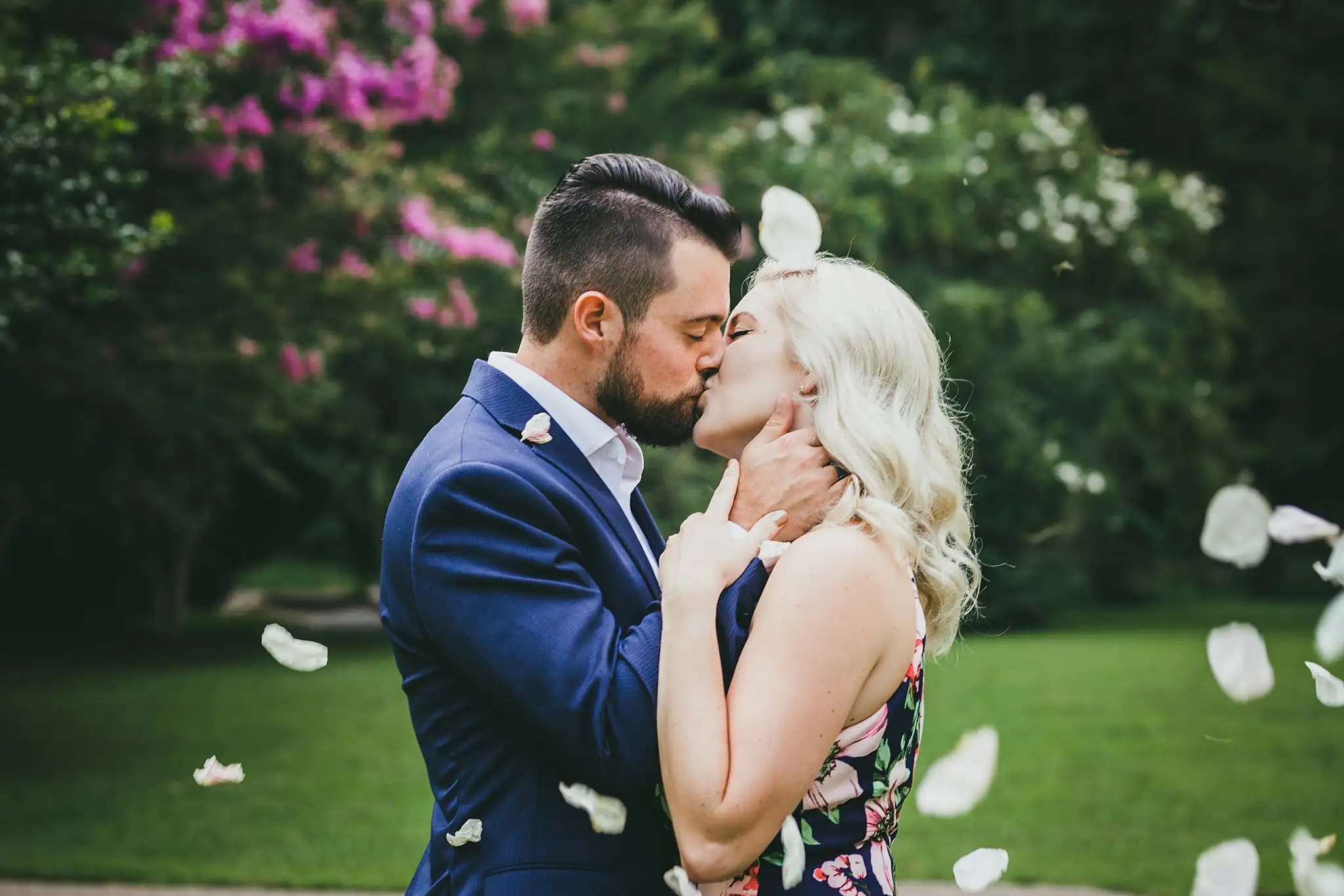AtlantaWeddingPhotographers_0560.jpg Engagement Portraits: a kiss on the lawn as petals come down, during their engagement session at Cator Woolford Gardens in Atlanta, GA