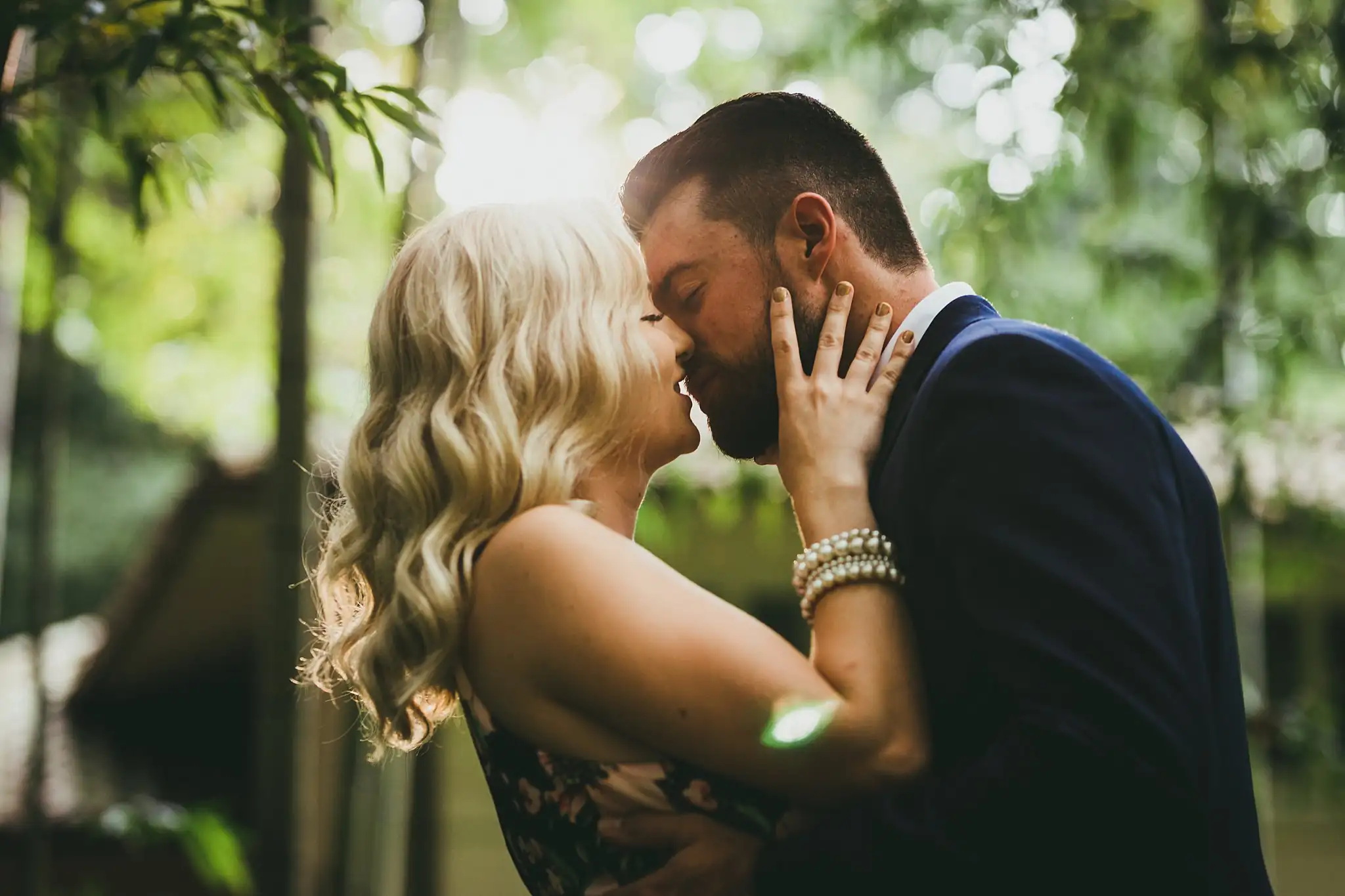 AtlantaWeddingPhotographers_0564.jpg Engagement Portraits: her hands at his face in the backlit greenery, during their engagement session at Cator Woolford Gardens in Atlanta, GA