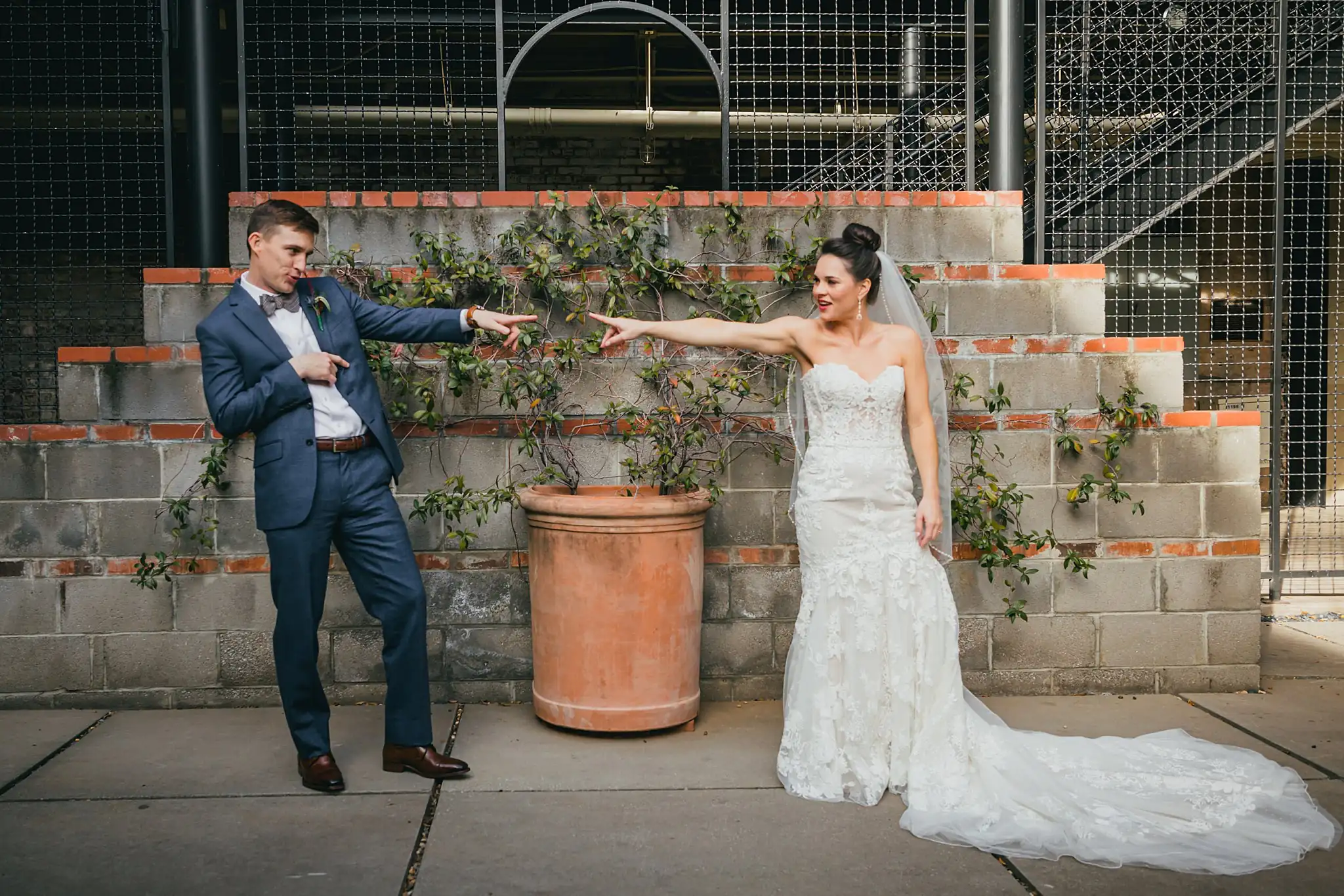 Wedding Formals: the couple pointing at each other across the courtyard, at their wedding at the Westside Warehouse in Atlanta, GA