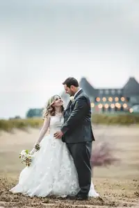 Wedding Formals: the couple in a field with the lit venue behind them, at a wedding