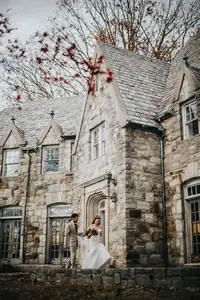Wedding Formals: the couple small against a stone Tudor house, at a wedding