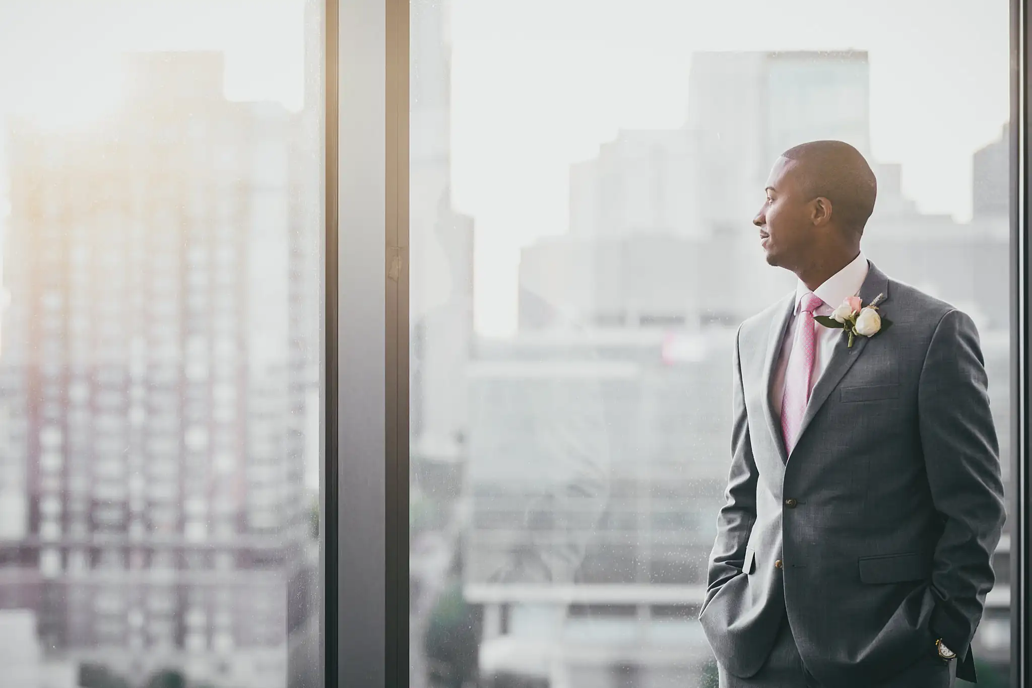 Getting Ready: the groom at the window in his light grey suit, before their elopement at Ventanas in Atlanta, GA