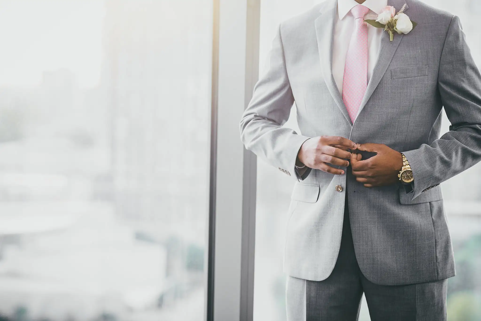 Getting Ready: the groom buttoning his jacket over his pink tie, before their elopement at Ventanas in Atlanta, GA
