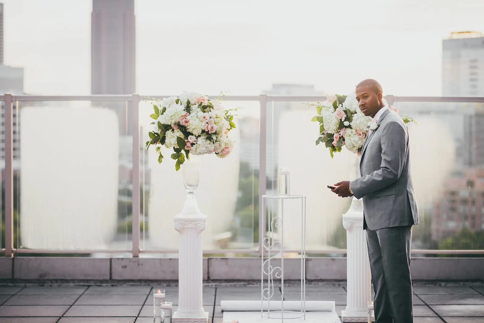 Wedding Ceremony: the groom waiting alone between the floral columns, at their elopement at Ventanas in Atlanta, GA