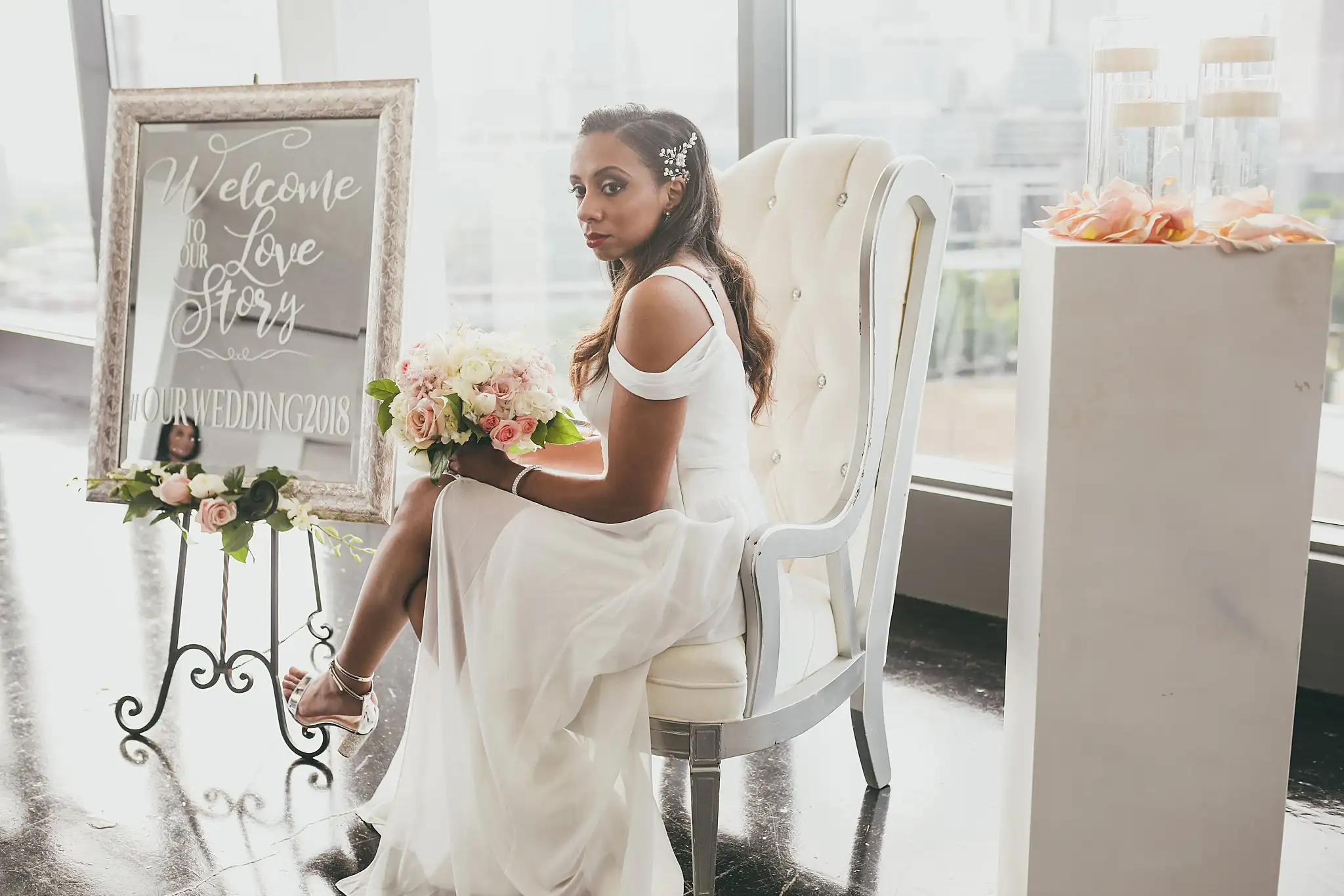 Bridal Portraits: the bride seated with her bouquet beside the welcome sign, at their elopement at Ventanas in Atlanta, GA
