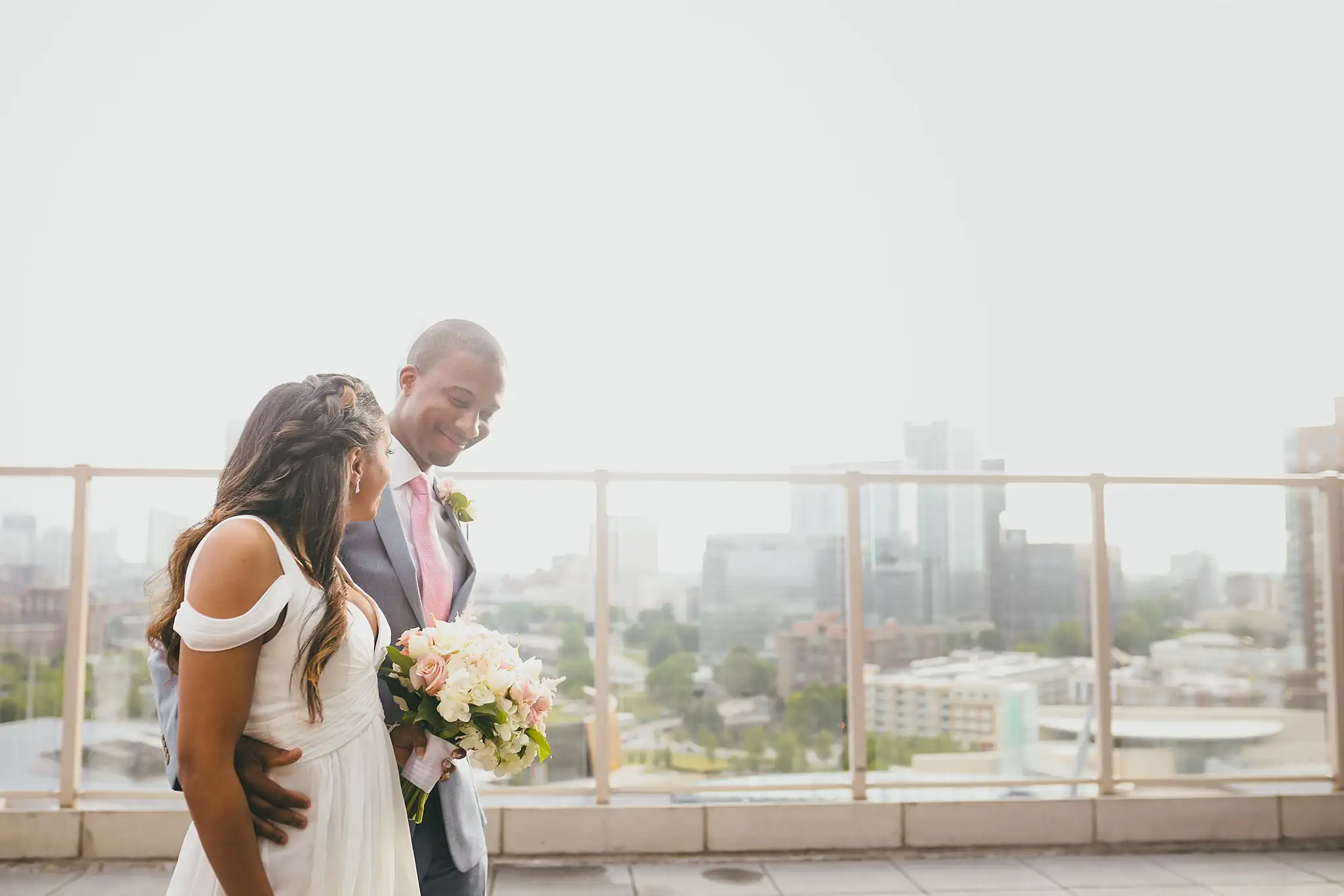 Wedding Formals: the couple at the rooftop rail with her bouquet, at their elopement at Ventanas in Atlanta, GA