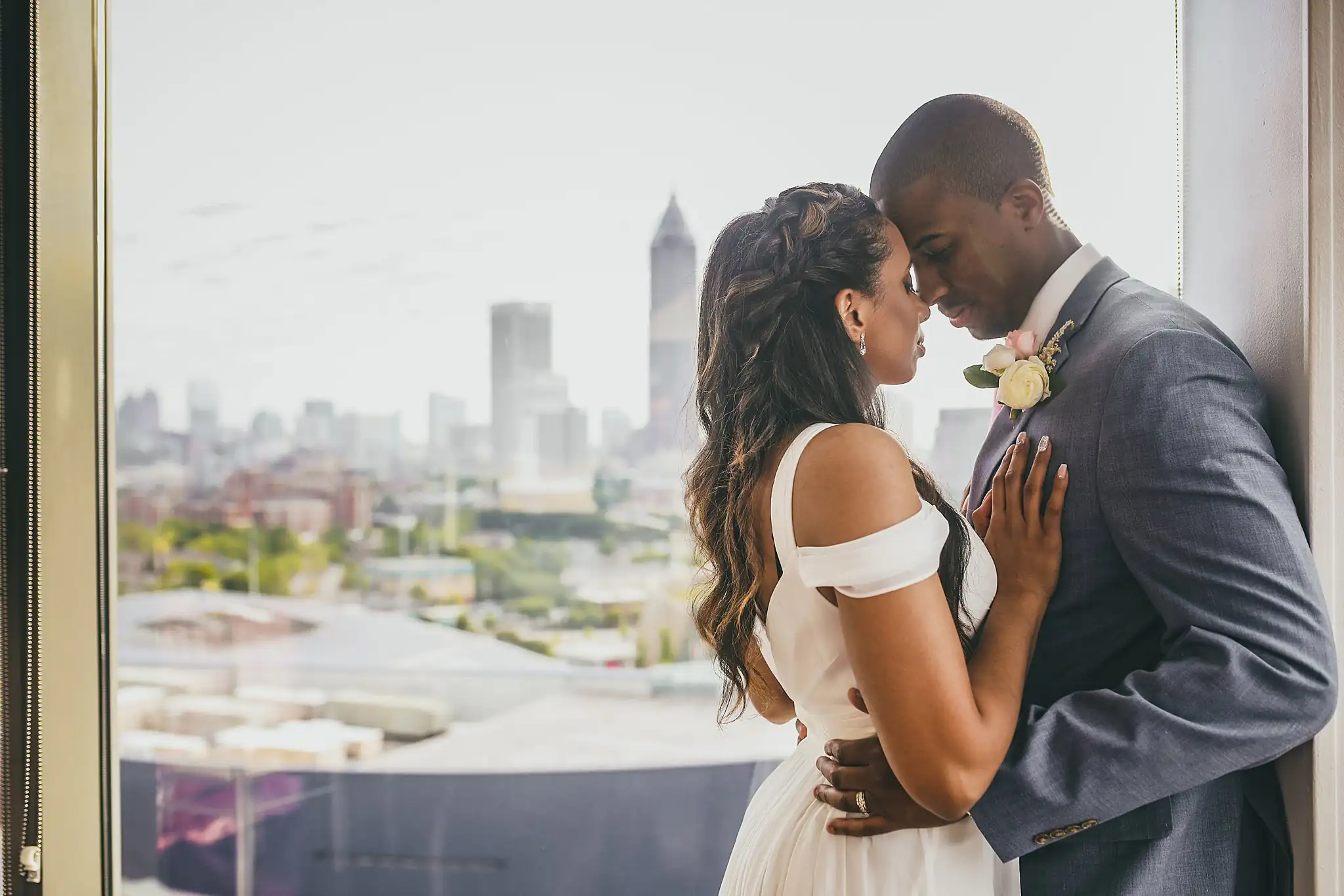 Wedding Formals: the couple close together at the window above the skyline, at their elopement at Ventanas in Atlanta, GA