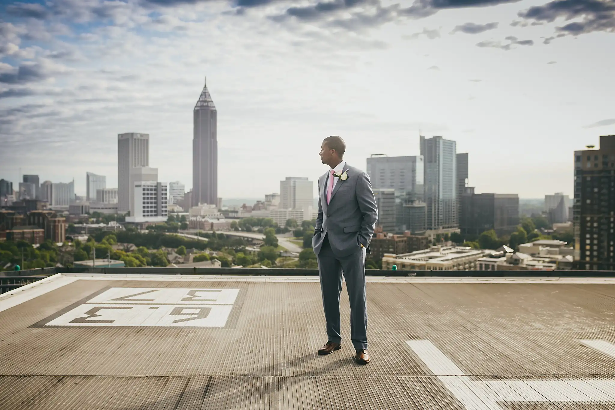 Portraits: the groom alone on the rooftop helipad above the skyline, at their elopement at Ventanas in Atlanta, GA