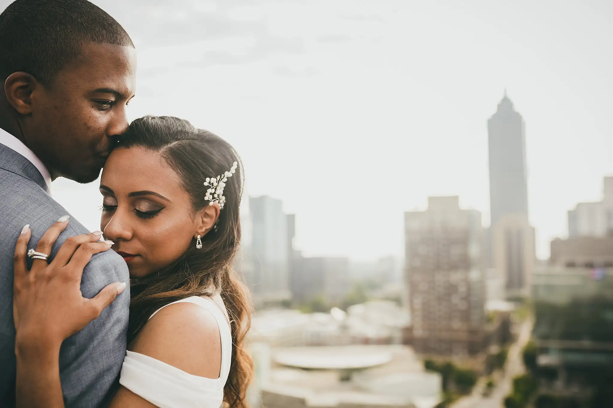 Wedding Formals: the groom kissing the bride's head on the rooftop above downtown, at their elopement at Ventanas in Atlanta, GA