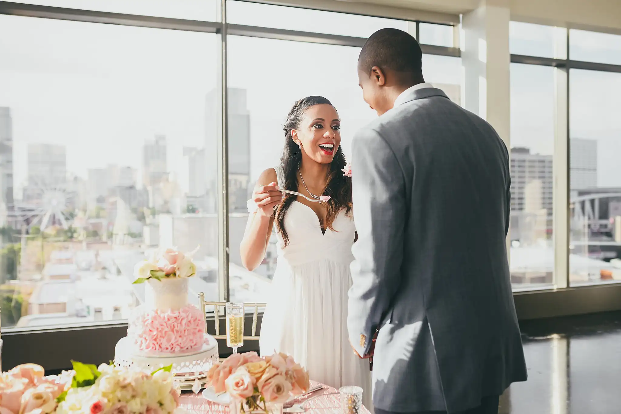 Cake Cutting: the bride feeding the groom a bite of cake above the skyline, at their elopement at Ventanas in Atlanta, GA
