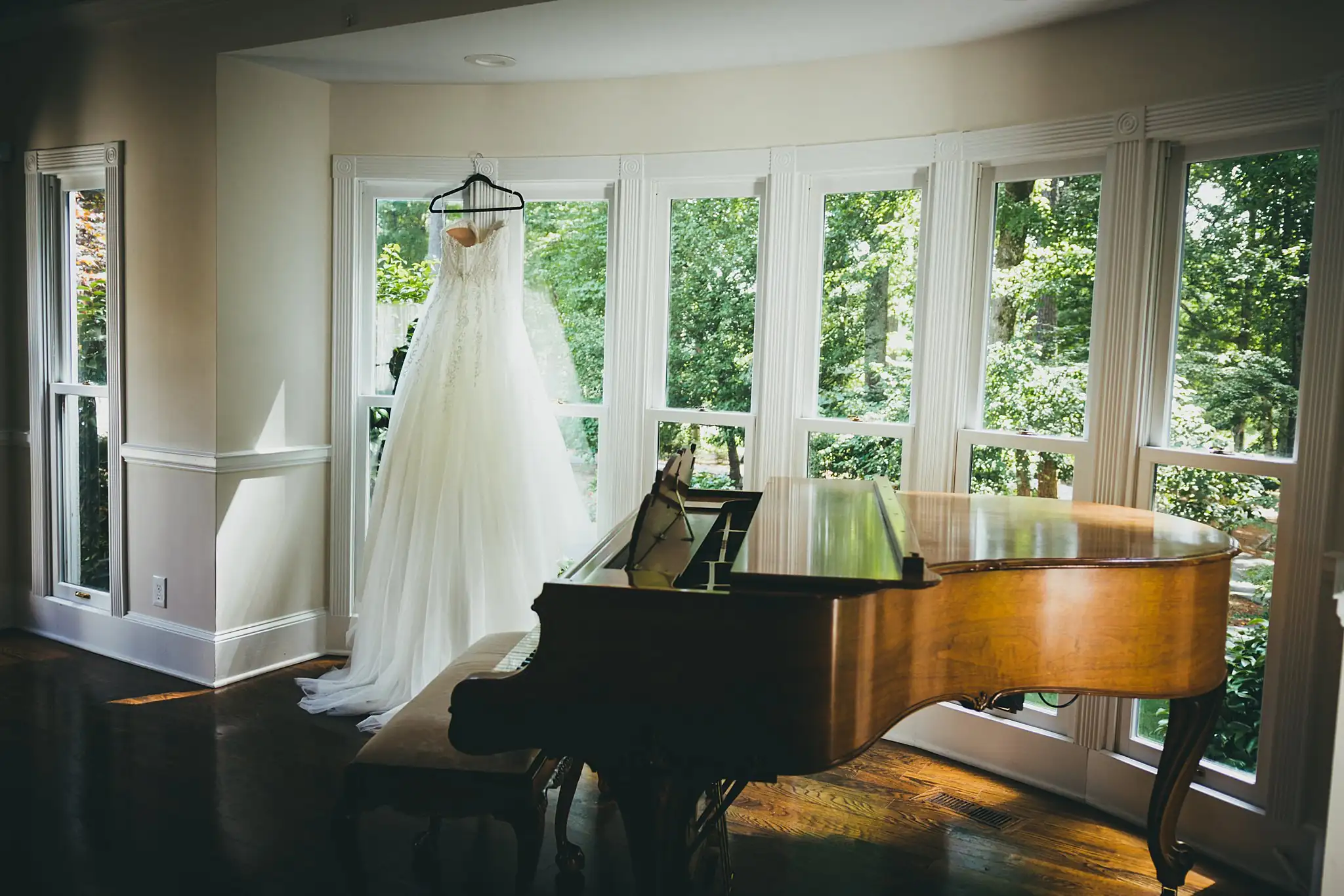 Wedding Details: the wedding gown hanging beside a grand piano, at a wedding at Little River Farms in Milton, GA