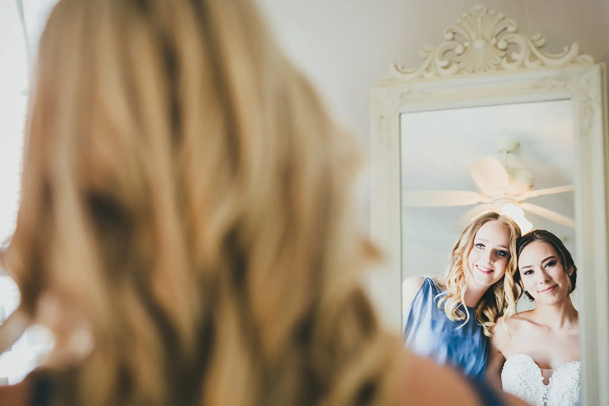 Getting Ready: the bride with a bridesmaid at the mirror, before their wedding at Little River Farms in Milton, GA