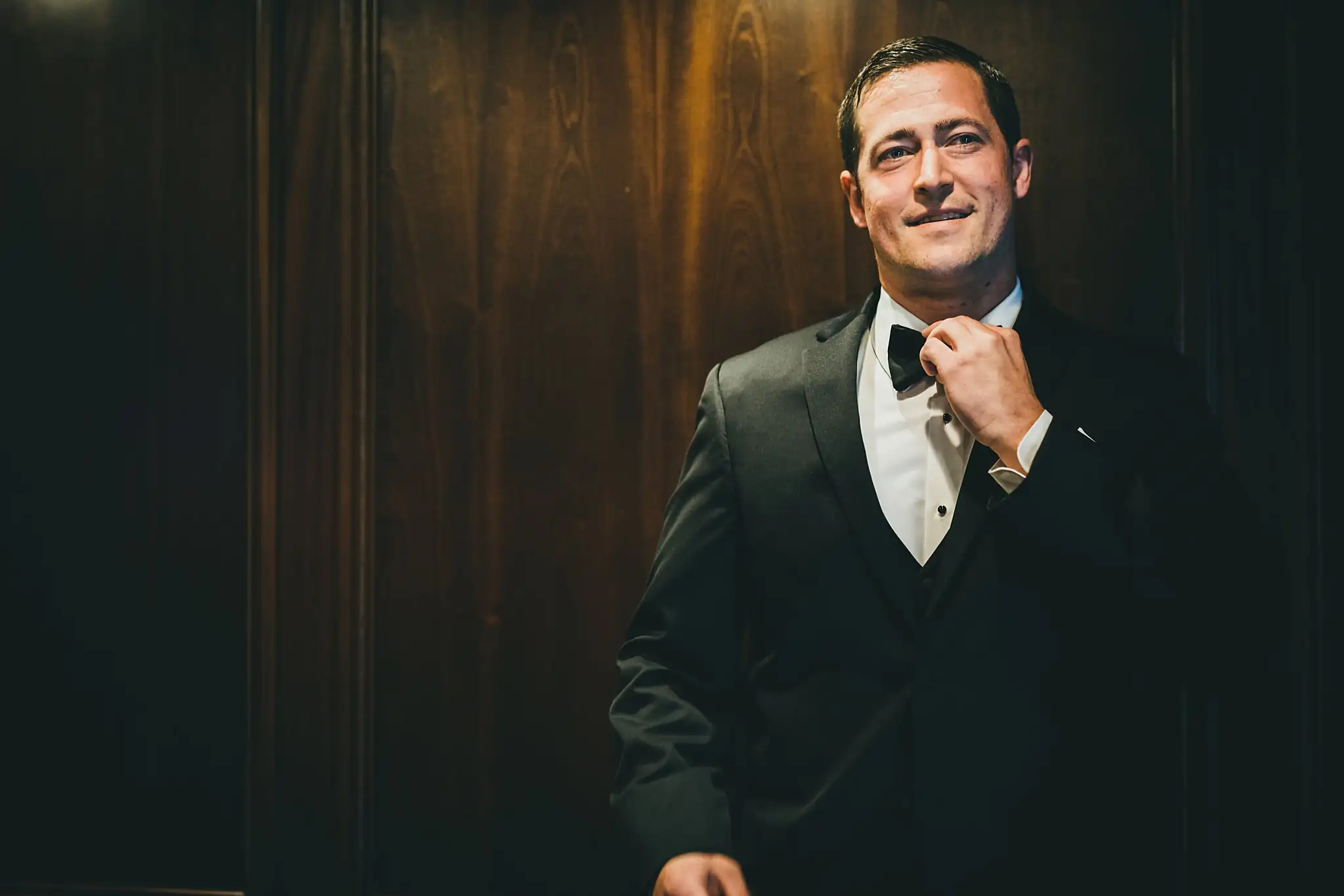 Getting Ready: the groom in his tuxedo against dark wood, before their wedding at Little River Farms in Milton, GA