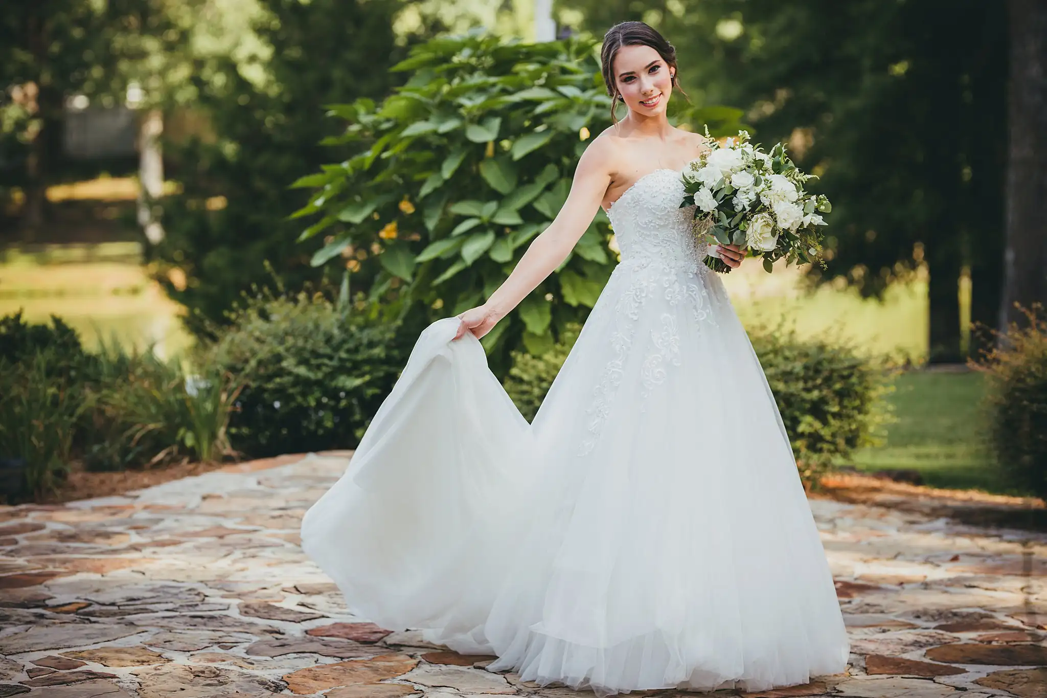 Bridal Portraits: the bride lifting her tulle skirt in the garden, at their wedding at Little River Farms in Milton, GA