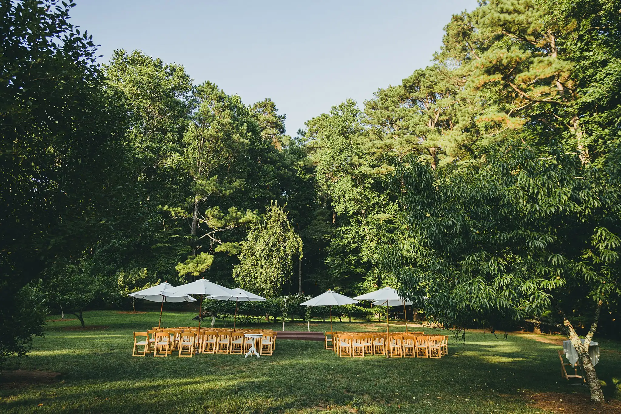 Wedding Ceremony: the ceremony lawn set with white umbrellas, at a wedding at Little River Farms in Milton, GA