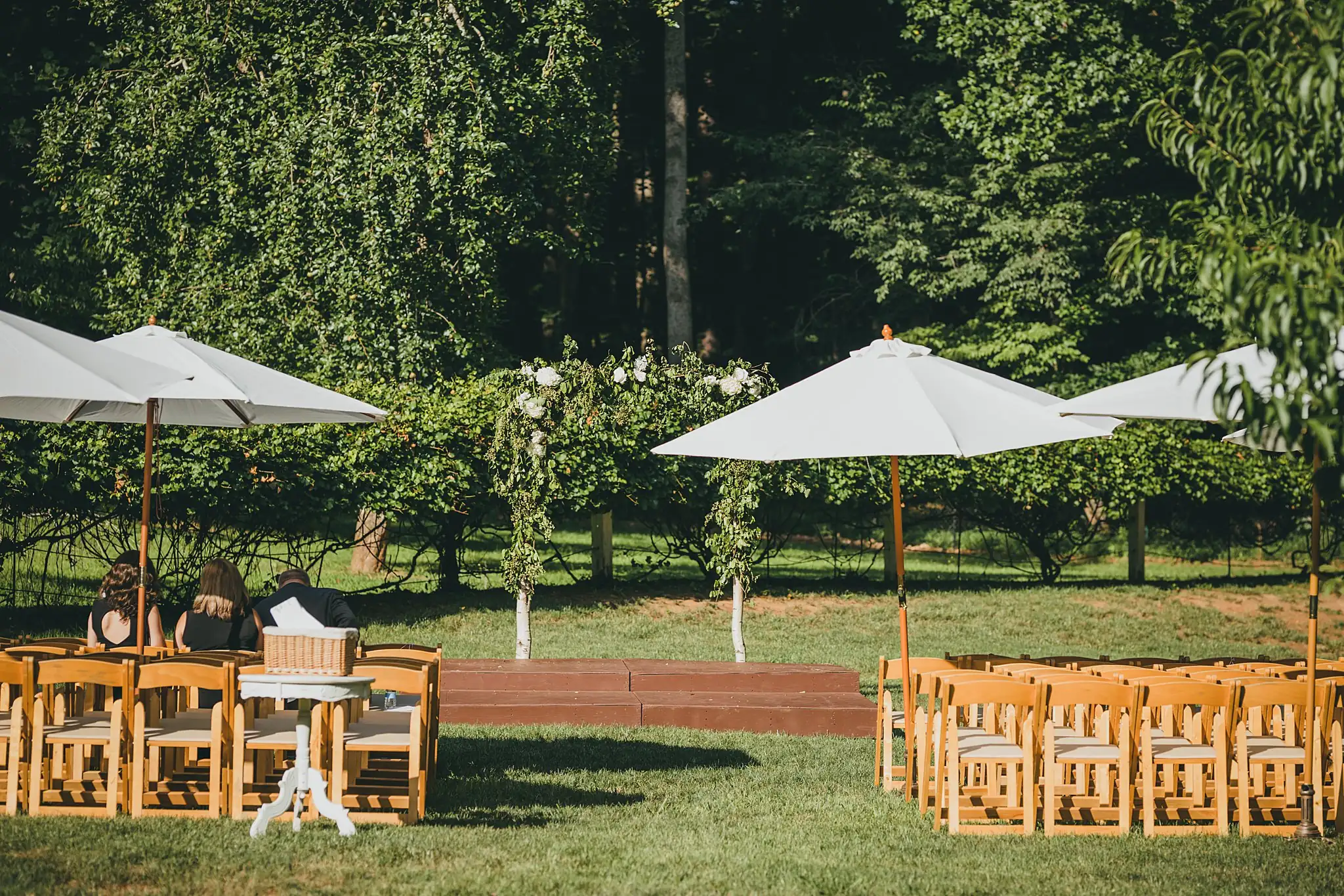 Wedding Ceremony: wooden chairs under umbrellas on the lawn, at a wedding at Little River Farms in Milton, GA