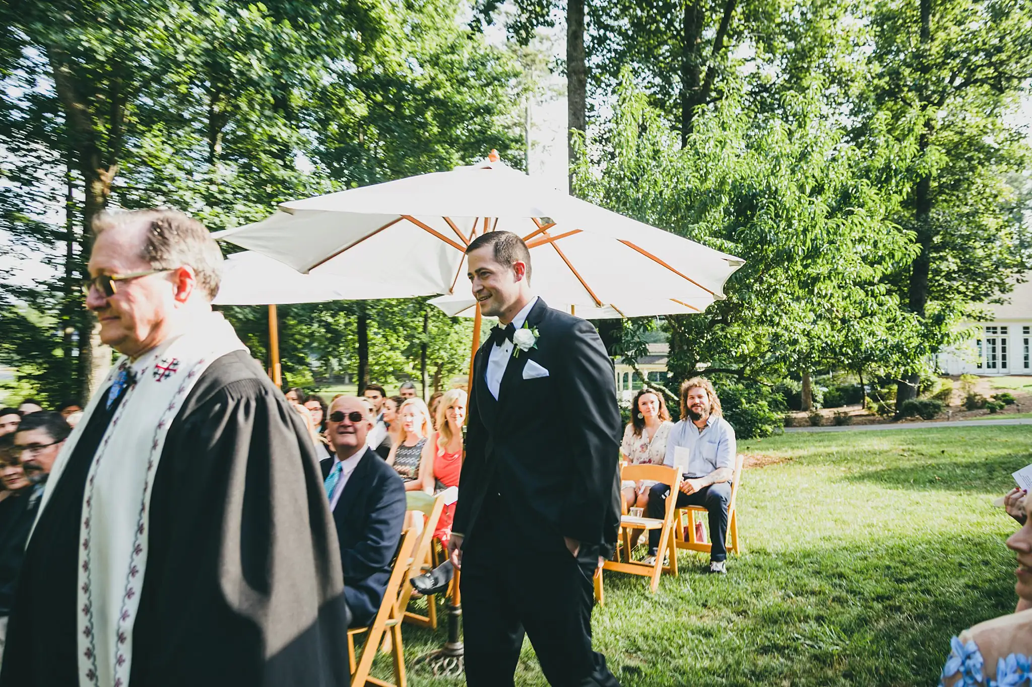 Wedding Ceremony: the groom at the front, guests under umbrellas, at their wedding at Little River Farms in Milton, GA