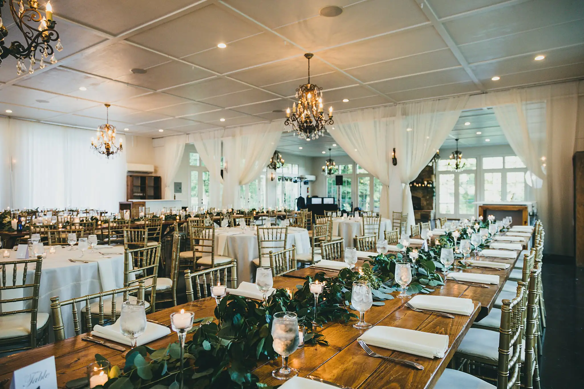 Reception Details: the pavilion set with long tables and greenery, at their wedding at Little River Farms in Milton, GA