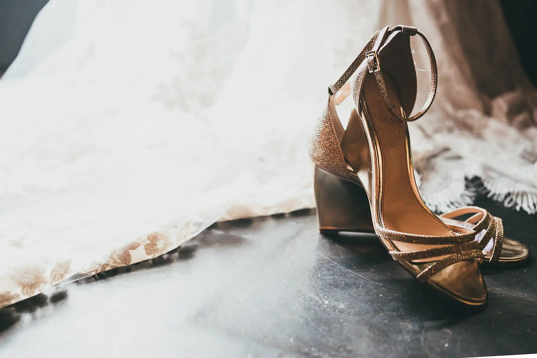 Wedding Details: the bride's gold heels beside her gown, at a wedding at the Piedmont Garden Tent in Atlanta, GA