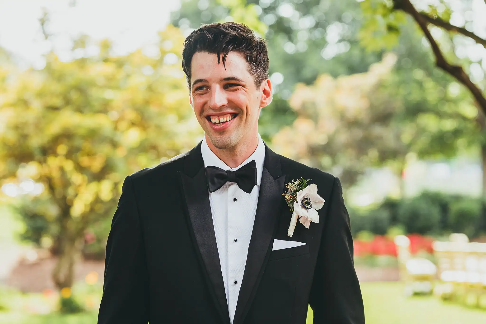 Wedding Formals: the groom smiling, anemone at his lapel, at their wedding at the Piedmont Garden Tent in Atlanta, GA