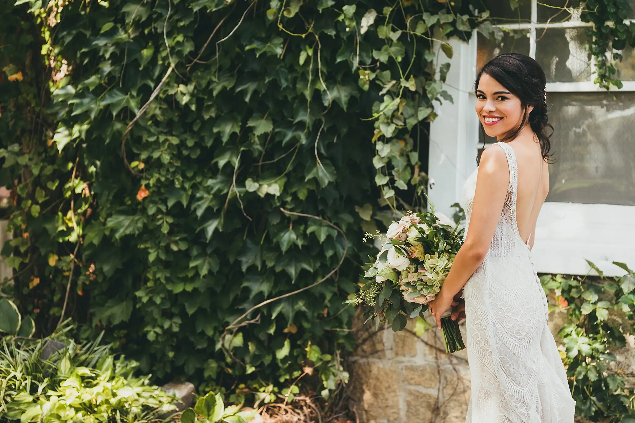 Bridal Portraits: the bride on the stone stair by an ivy wall, at their wedding at the Piedmont Garden Tent in Atlanta, GA