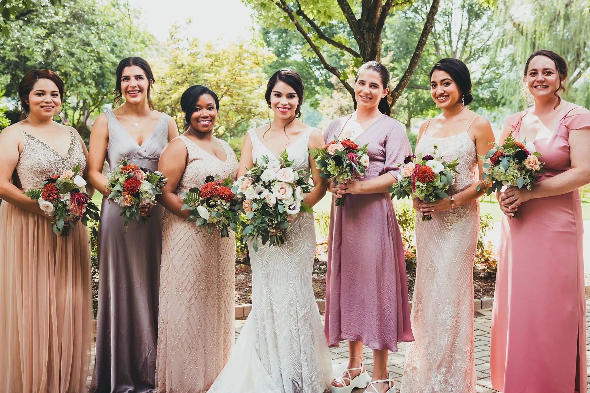 Wedding Party: the bridesmaids in blush and mauve with bouquets, at their wedding at the Piedmont Garden Tent in Atlanta, GA