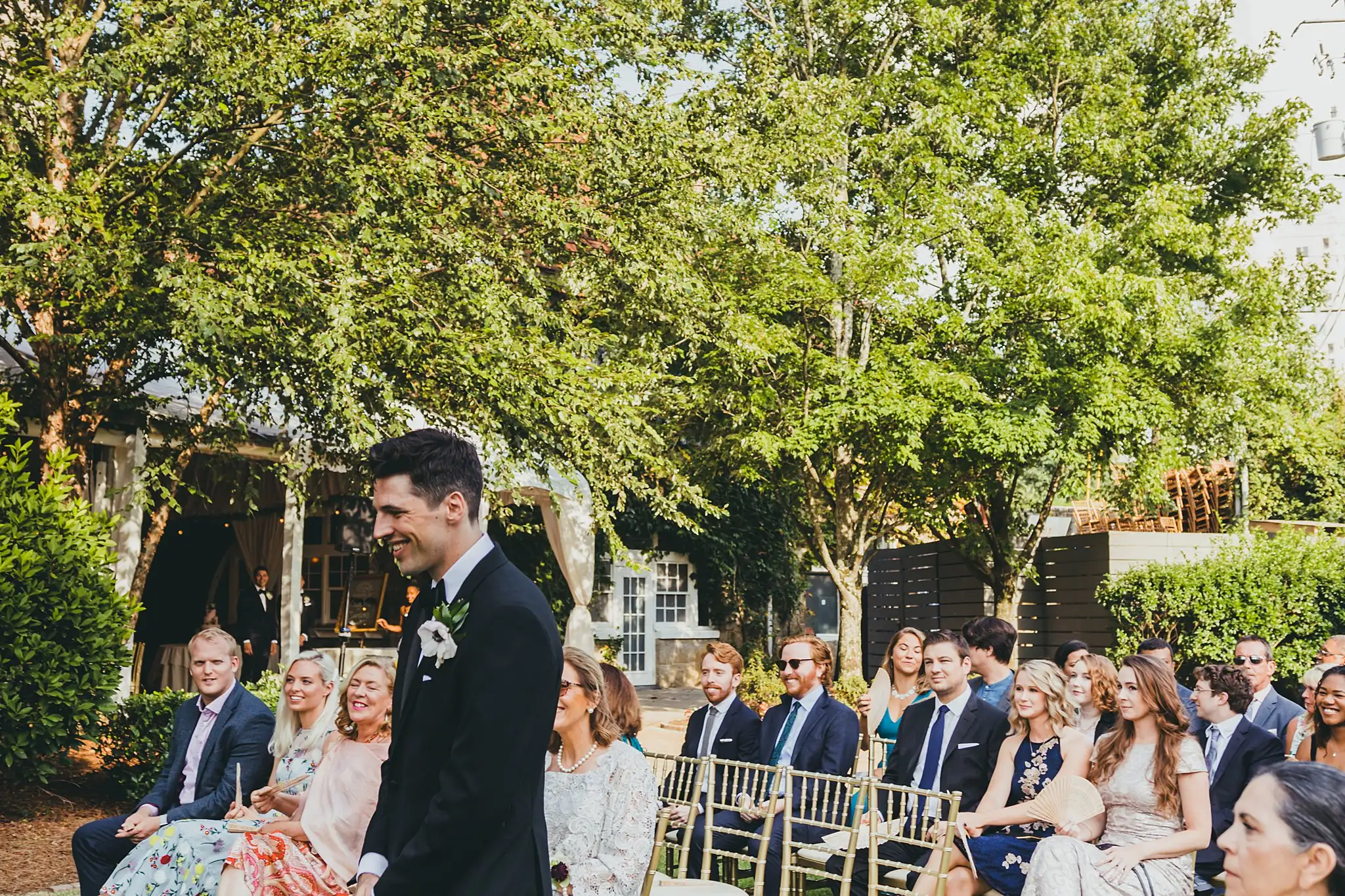 Wedding Ceremony: the groom seated among the guests beforehand, at their wedding at the Piedmont Garden Tent in Atlanta, GA