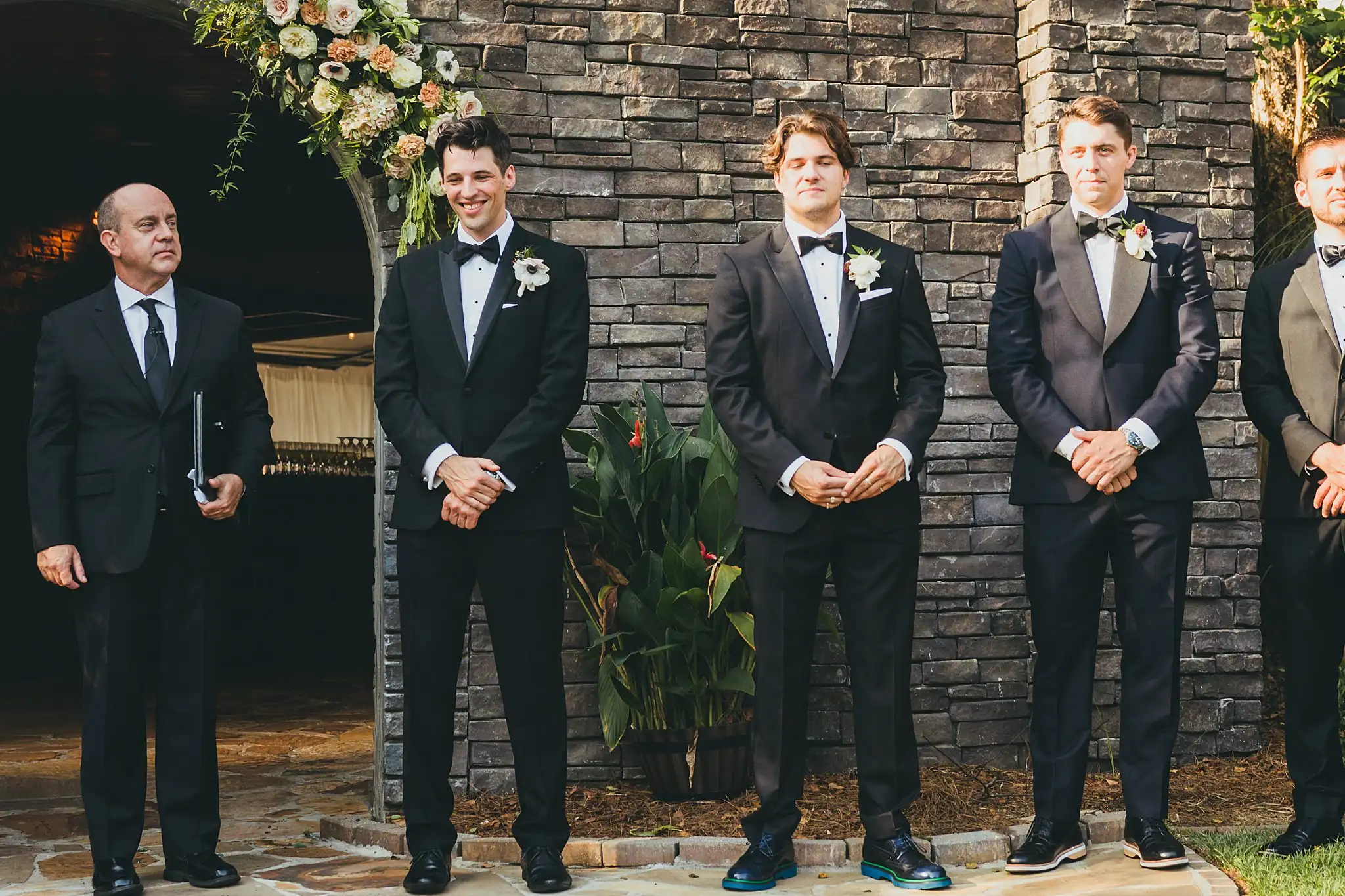Wedding Ceremony: the groom and groomsmen at the stone wall, at their wedding at the Piedmont Garden Tent in Atlanta, GA