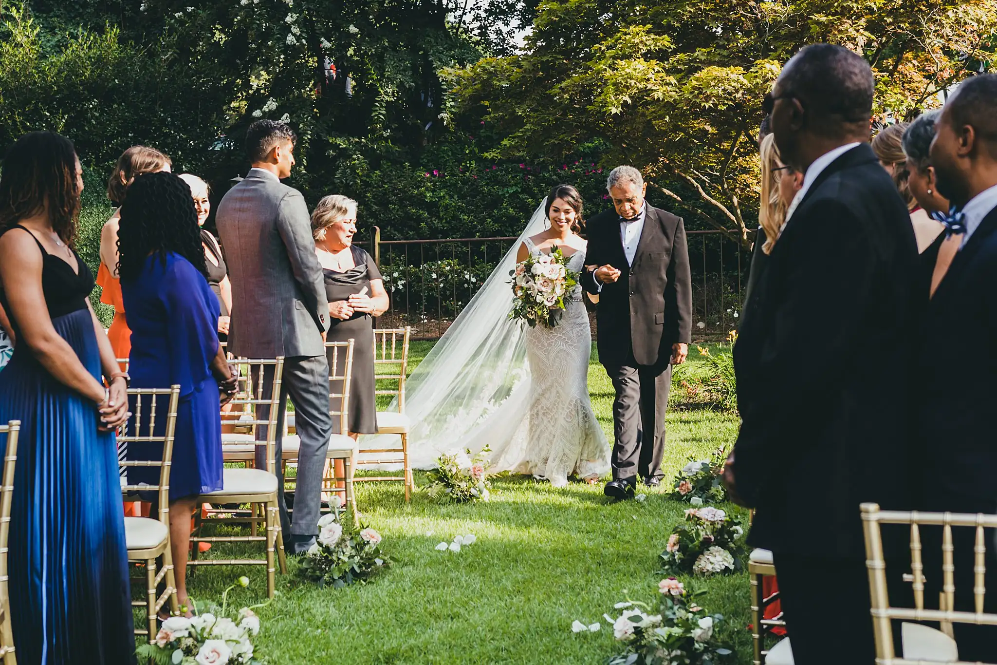 Processional: the bride coming down the aisle on her father's arm, at their wedding at the Piedmont Garden Tent in Atlanta, GA