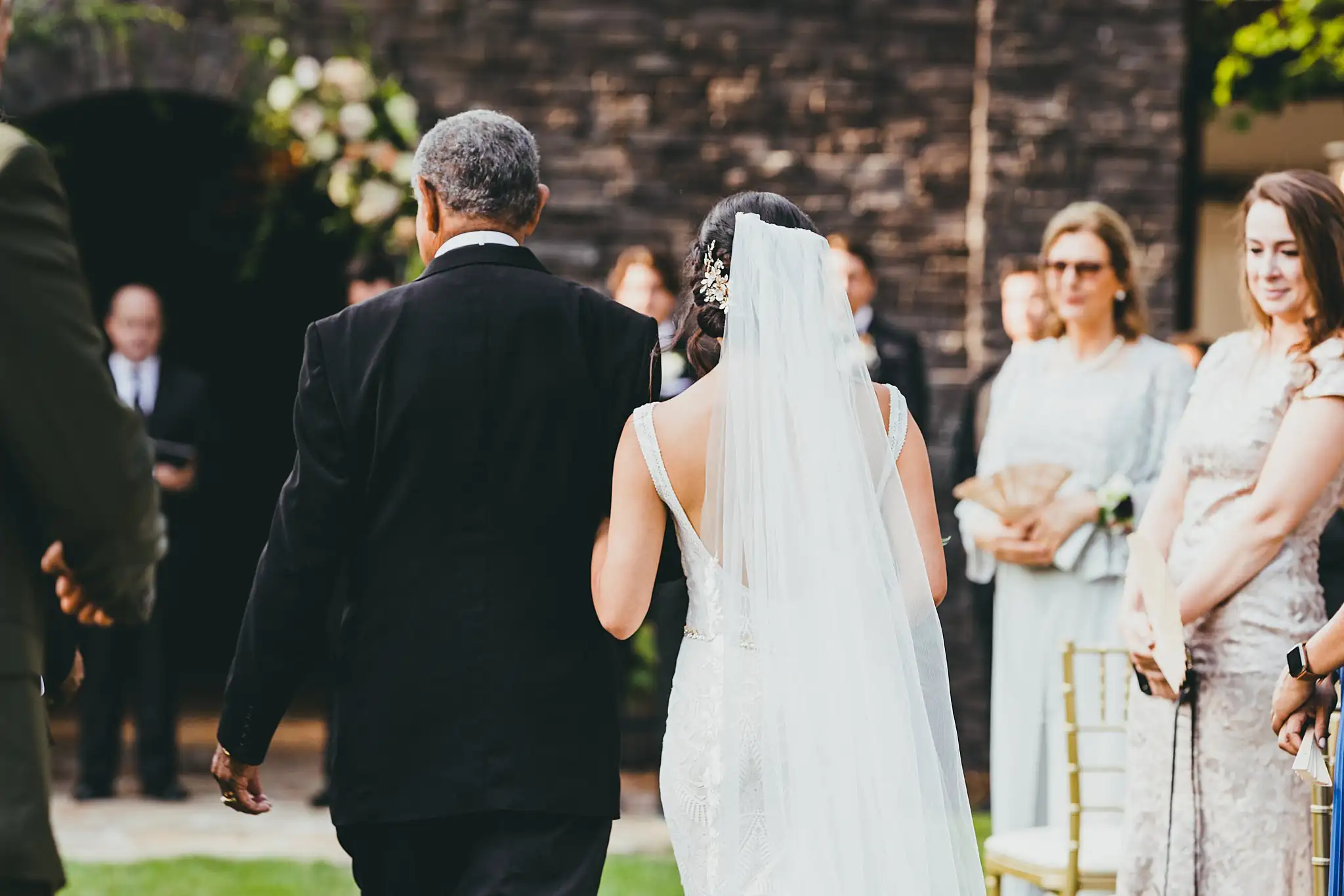 Processional: the bride and her father from behind, veil trailing, at their wedding at the Piedmont Garden Tent in Atlanta, GA