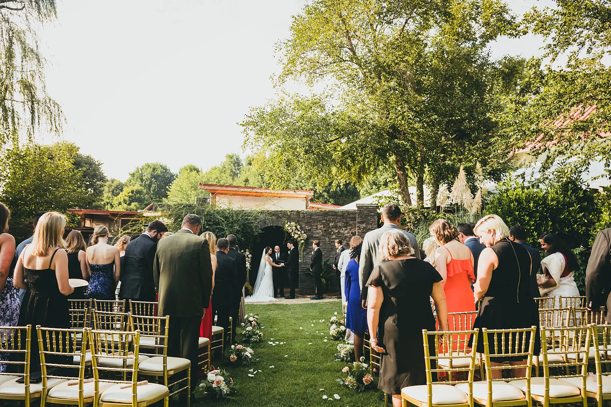 Wedding Ceremony: the ceremony from behind the guests on the lawn, at their wedding at the Piedmont Garden Tent in Atlanta, GA