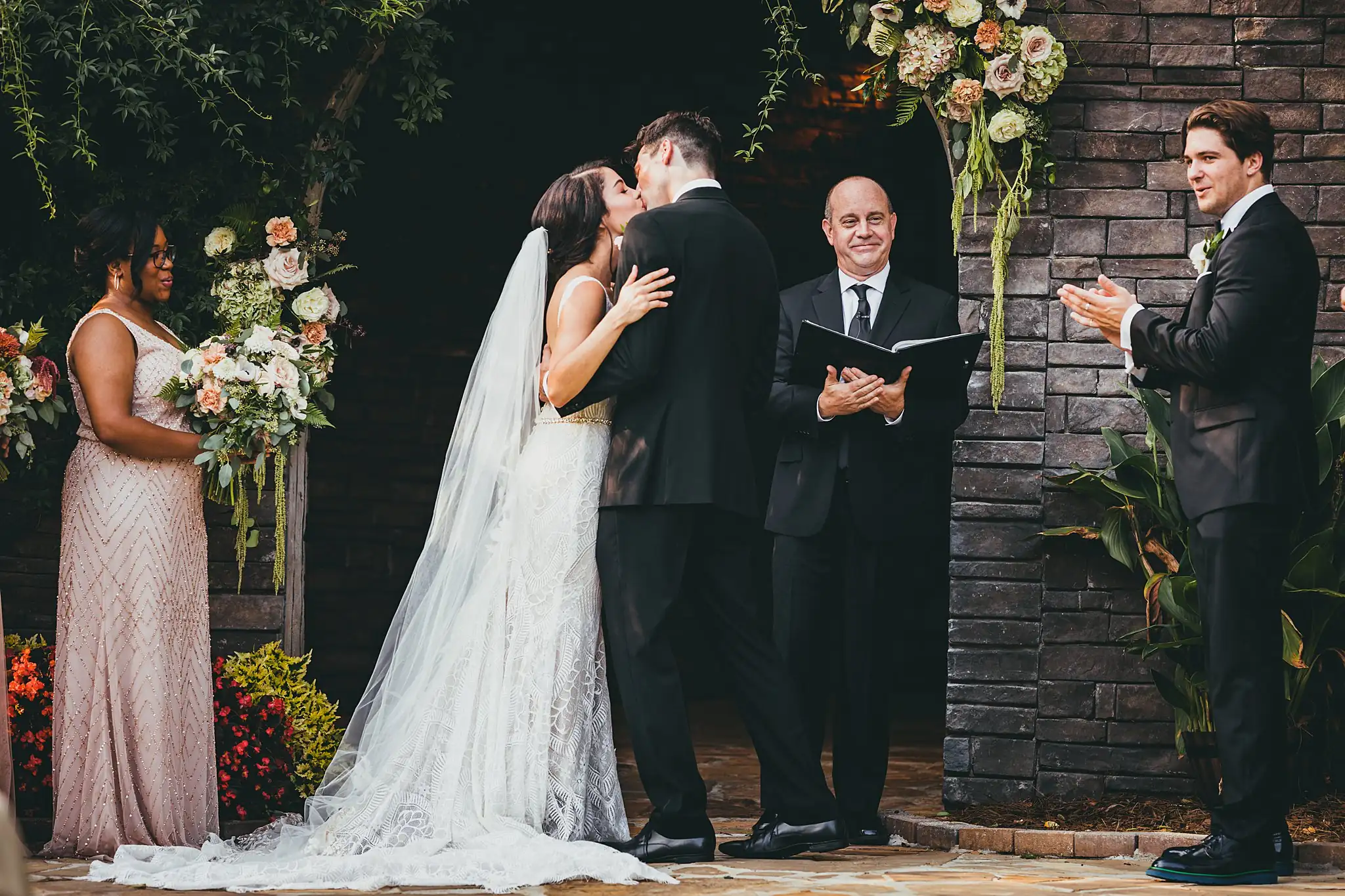 Wedding Ceremony: the first kiss at the flower-topped stone wall, at their wedding at the Piedmont Garden Tent in Atlanta, GA