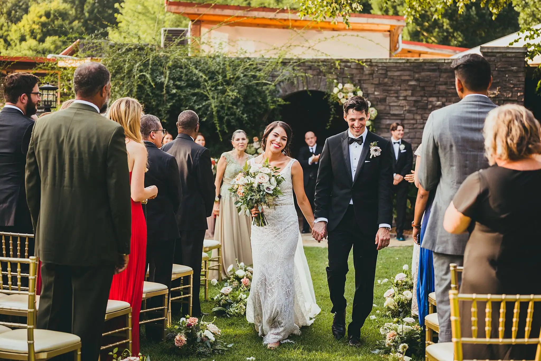 Recessional: the couple coming out through their guests, at their wedding at the Piedmont Garden Tent in Atlanta, GA