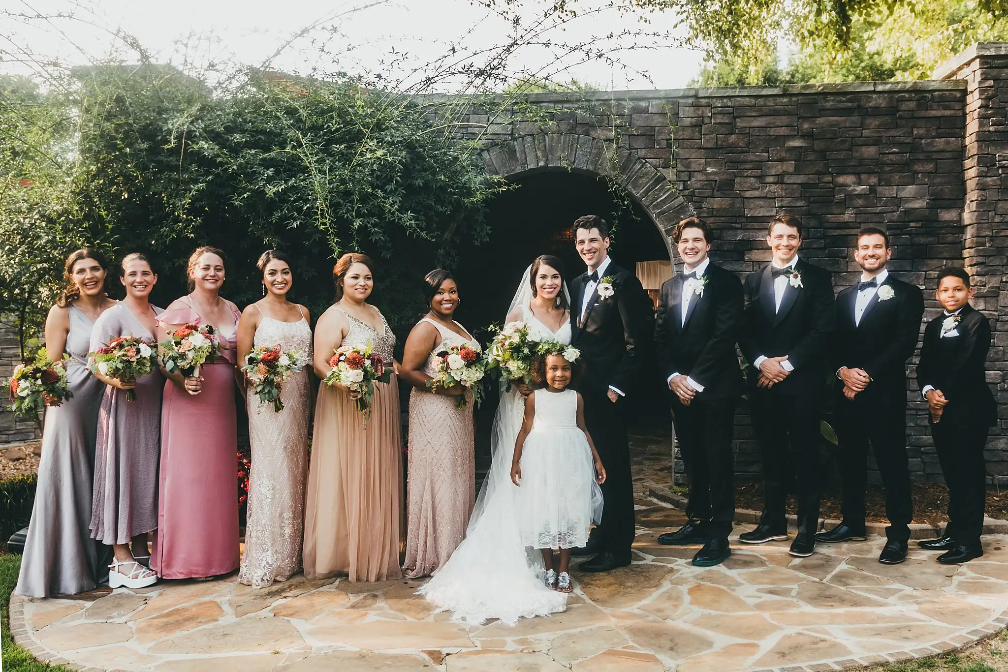 Wedding Party: the full bridal party on the stone terrace, at their wedding at the Piedmont Garden Tent in Atlanta, GA
