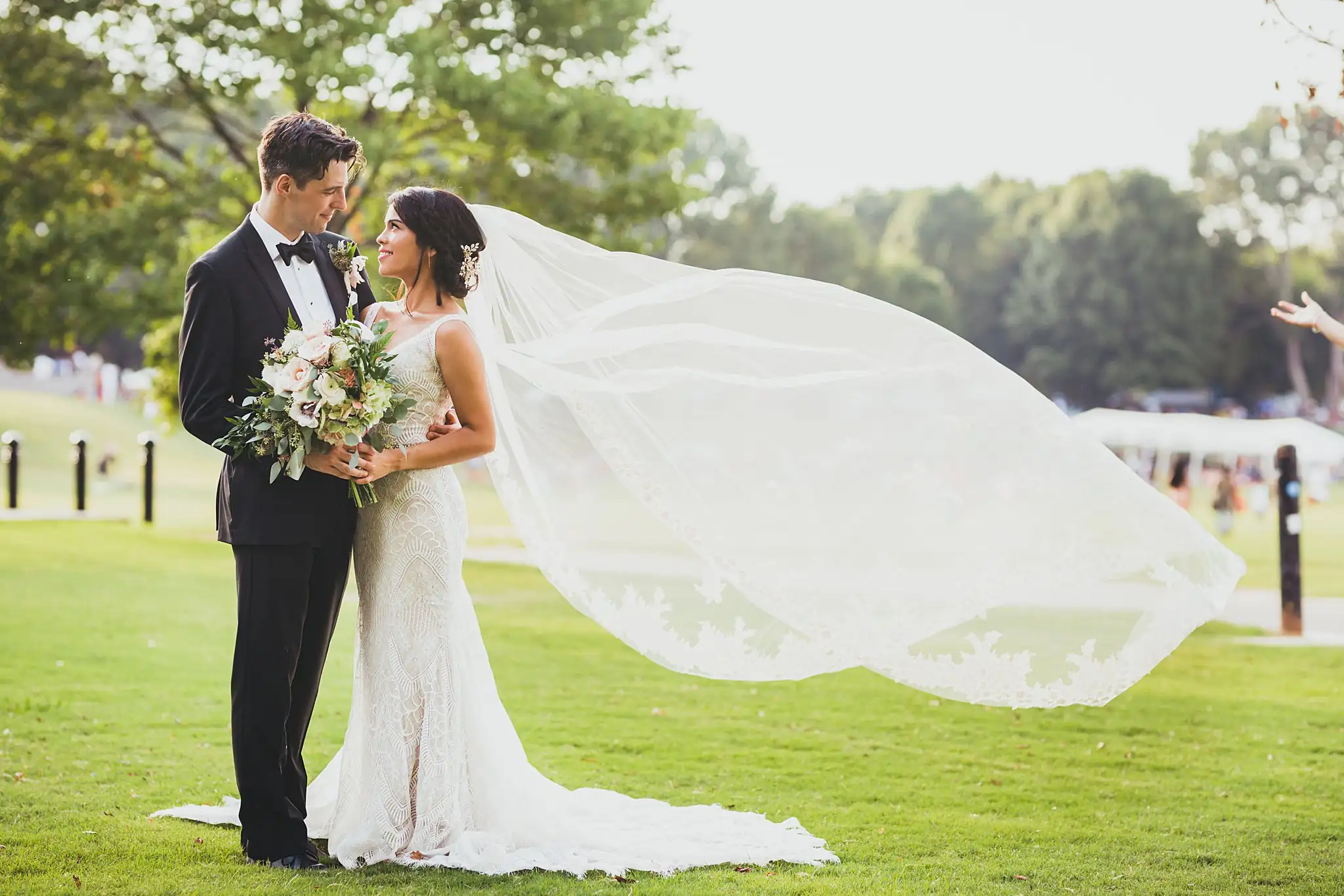 Wedding Formals: the couple on the park lawn, her veil streaming, at their wedding at the Piedmont Garden Tent in Atlanta, GA