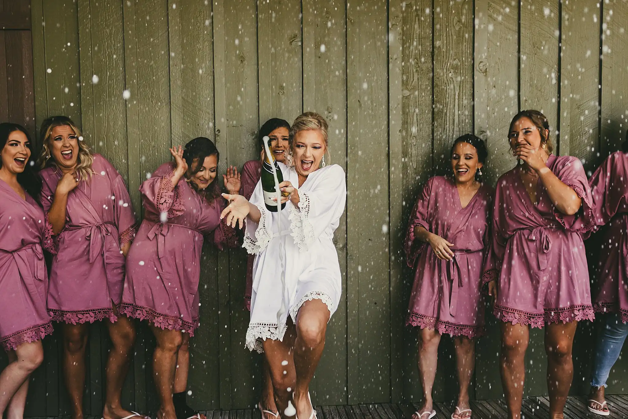 Getting Ready: the bridesmaids spraying champagne, all laughing, before their wedding at Houston Lake Country Club in Perry, GA