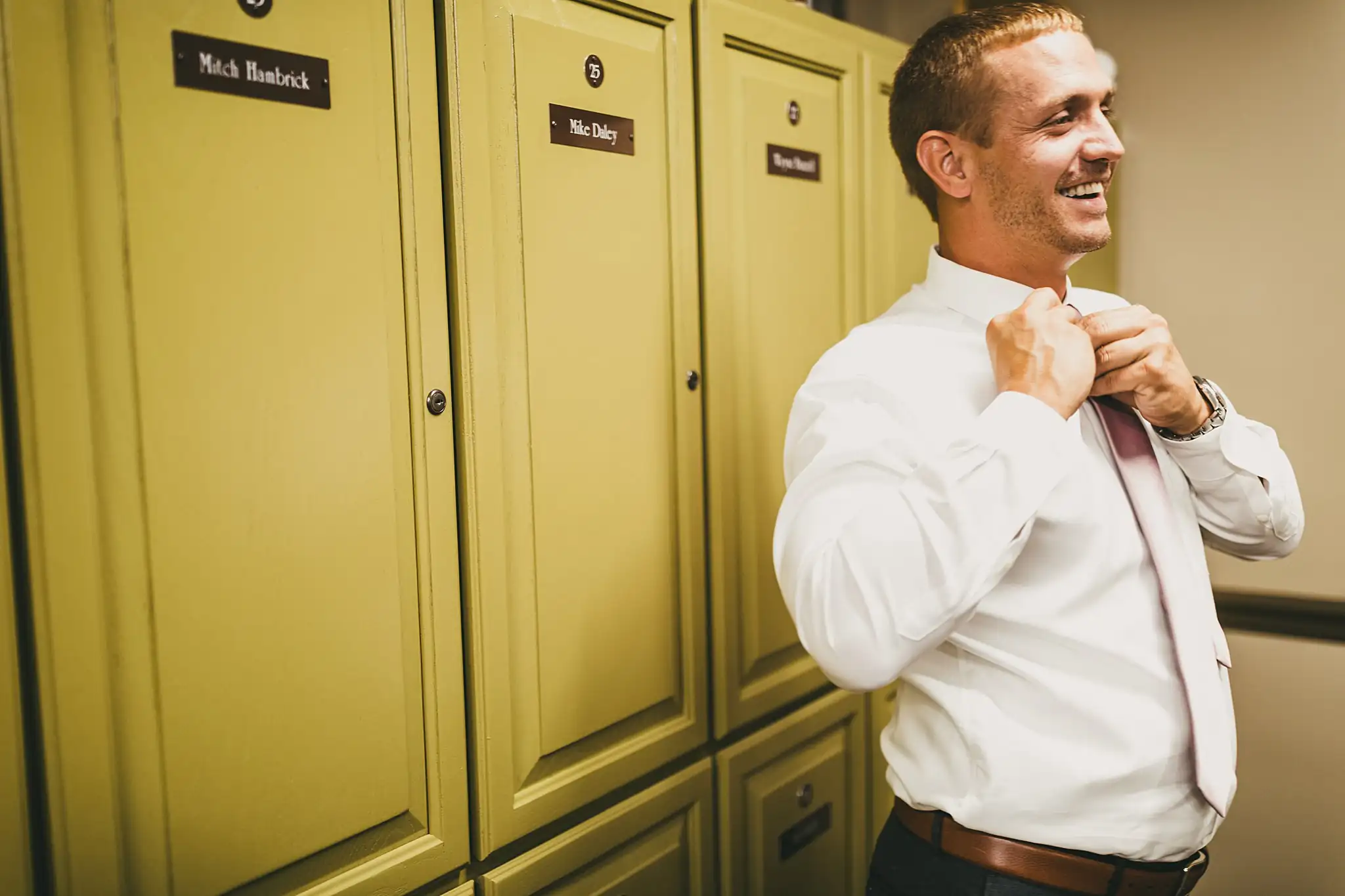 Getting Ready: the groom fixing his tie by the lockers, before their wedding at Houston Lake Country Club in Perry, GA