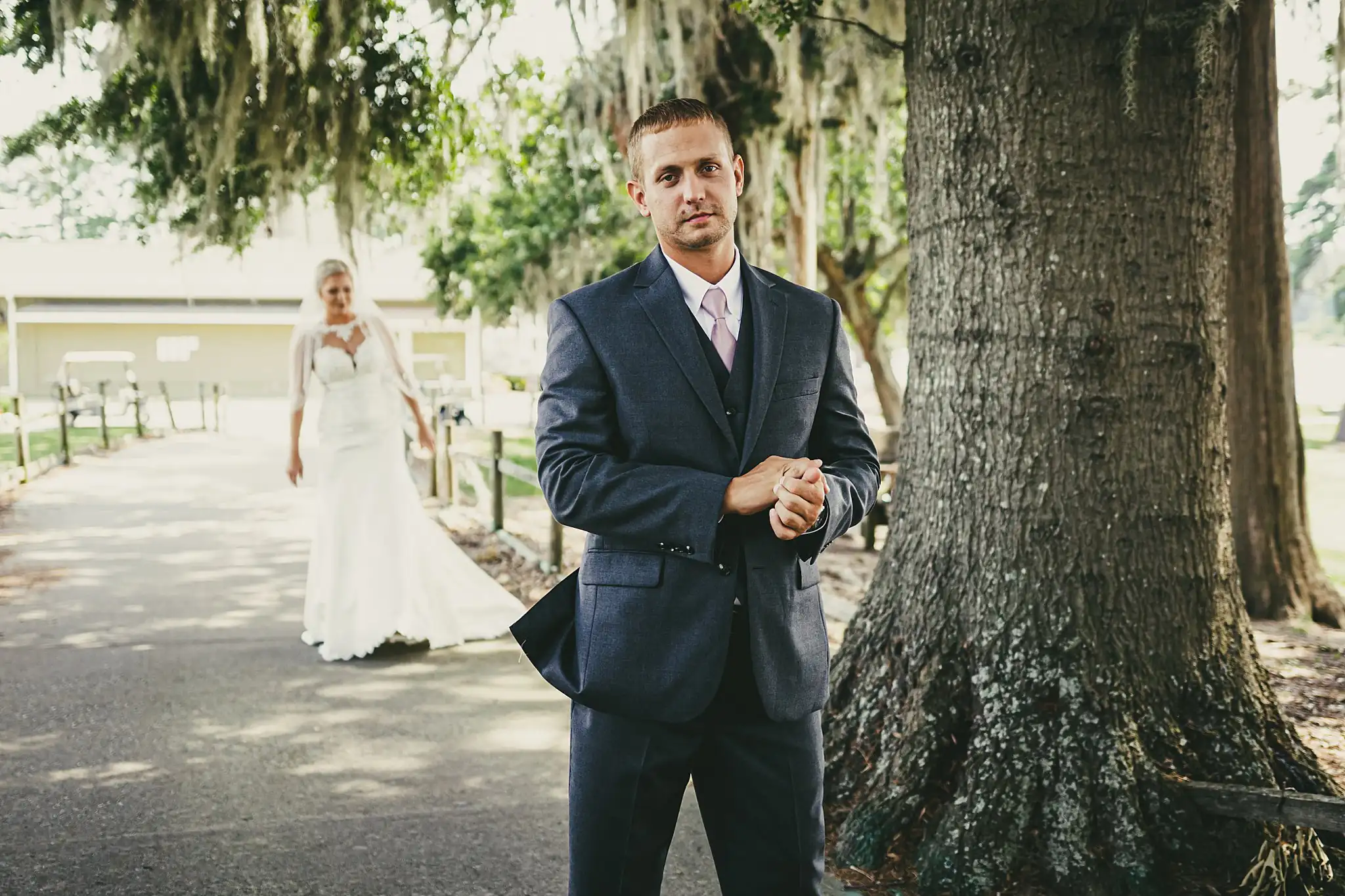 First Look: the groom waiting by a moss-draped oak, before their wedding at Houston Lake Country Club in Perry, GA