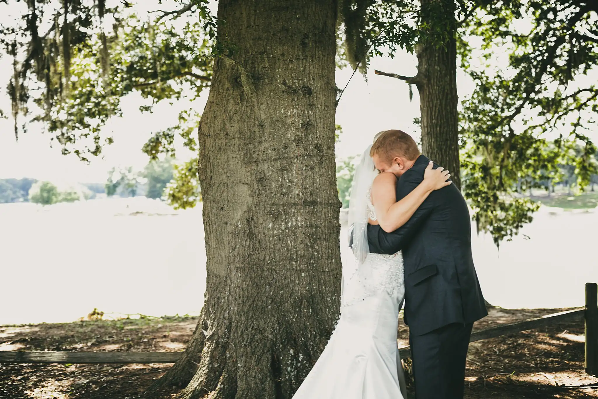 First Look: the couple holding each other under the oak, before their wedding at Houston Lake Country Club in Perry, GA