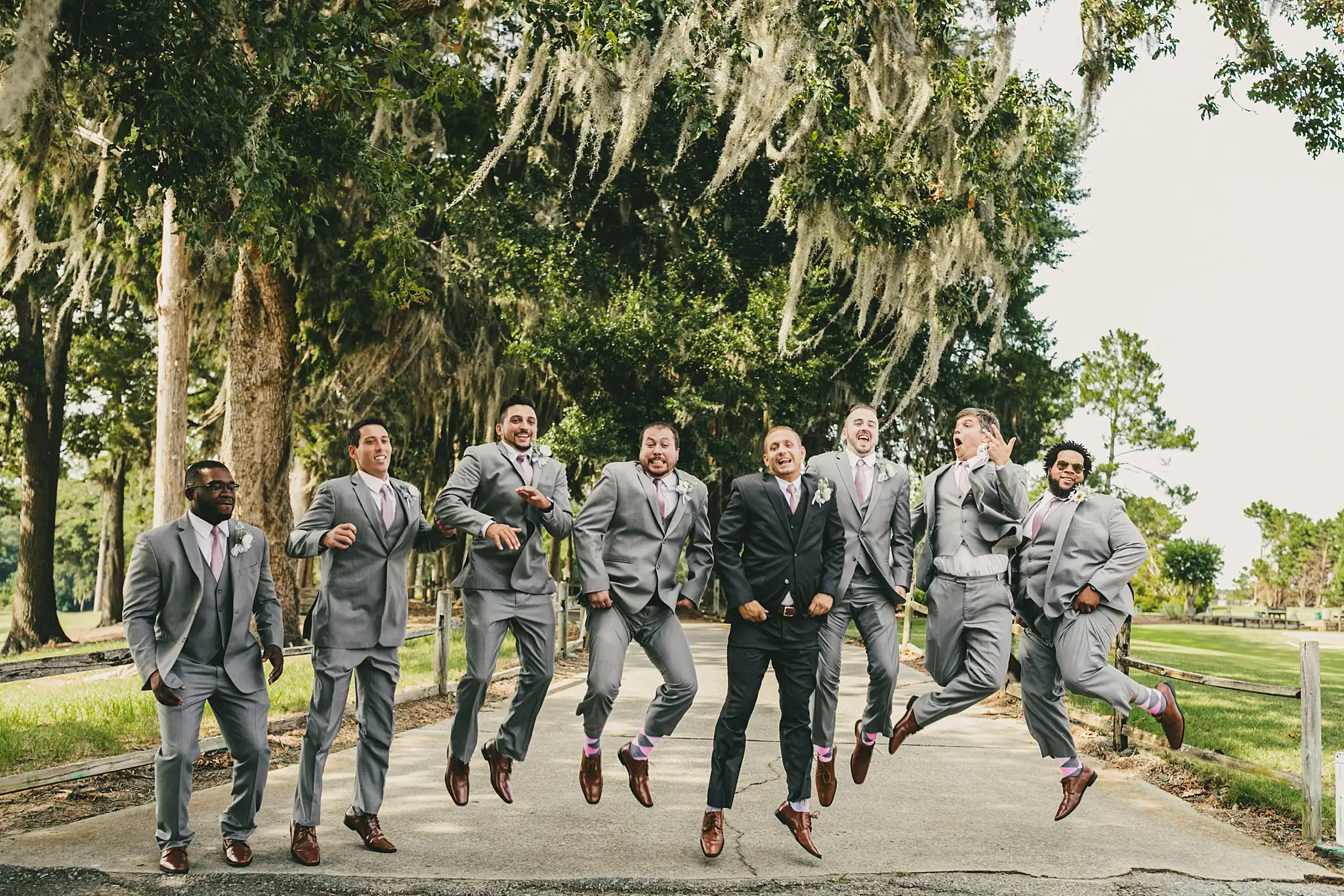 Wedding Party: the groomsmen in grey suits leaping in the air, at their wedding at Houston Lake Country Club in Perry, GA