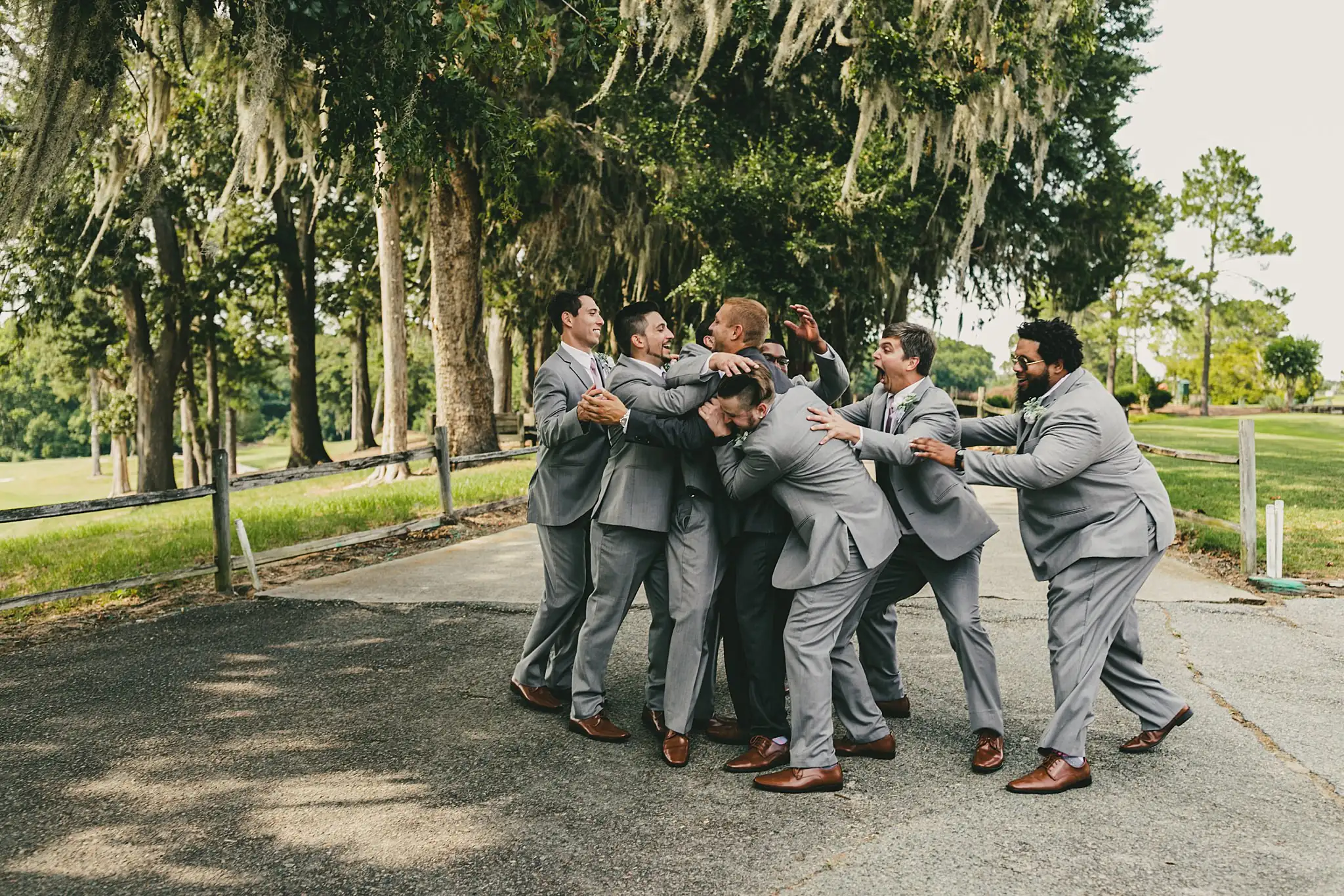 Wedding Party: the groomsmen mobbing the groom, laughing, at their wedding at Houston Lake Country Club in Perry, GA