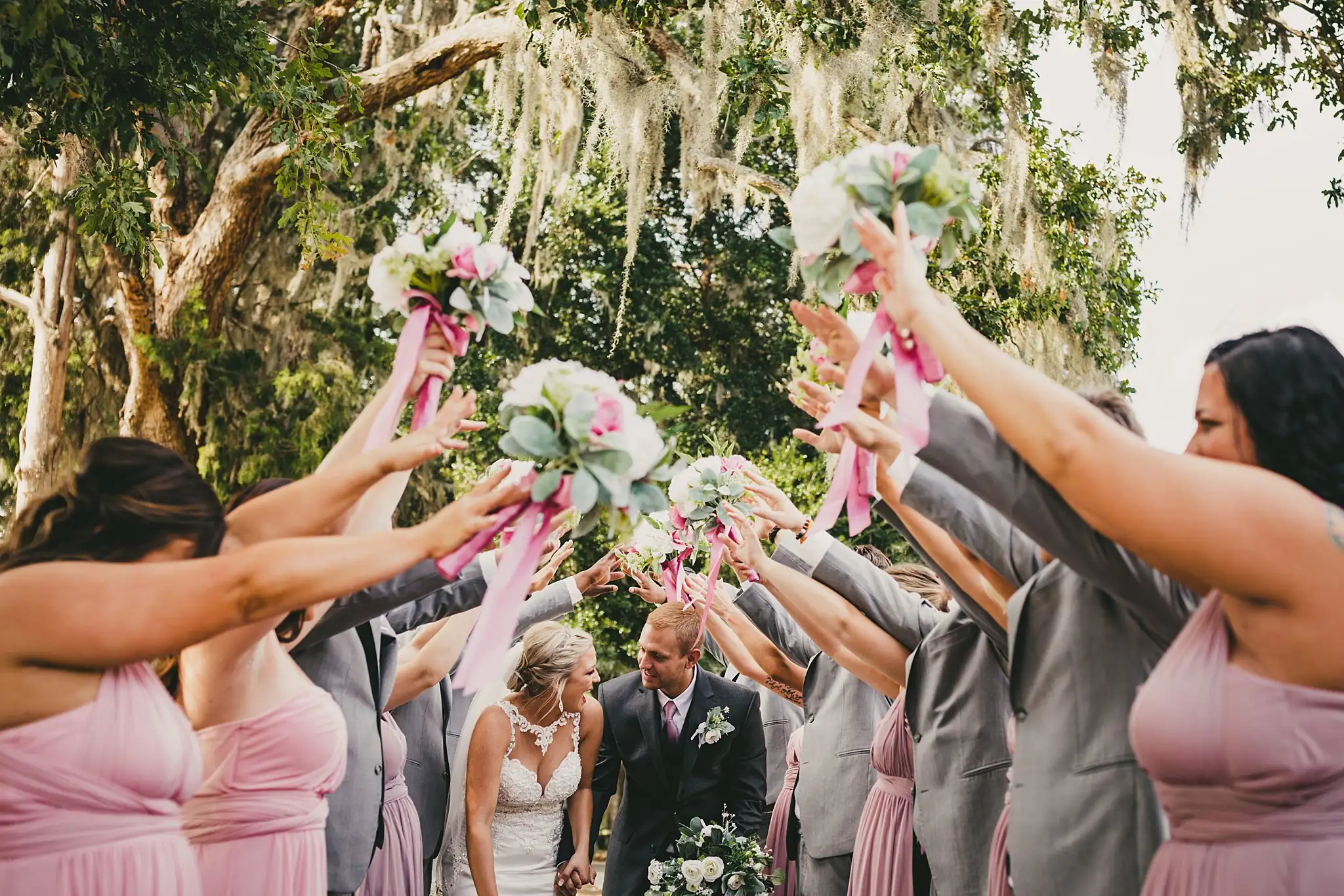 Wedding Party: the bridal party raising bouquets over the couple, at their wedding at Houston Lake Country Club in Perry, GA