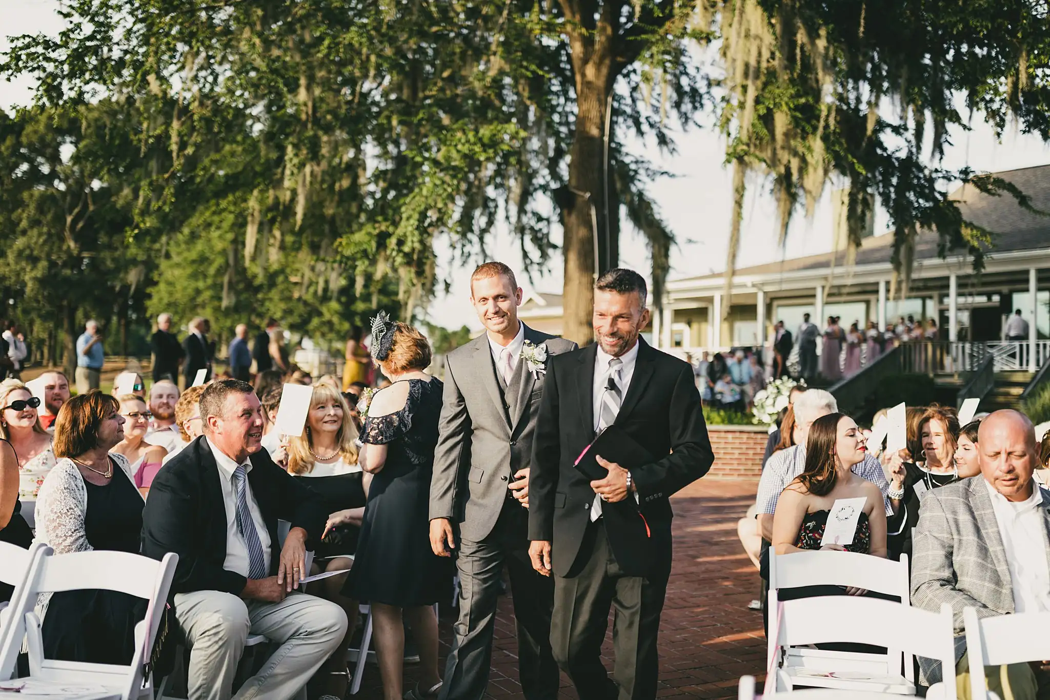 Processional: groomsmen seating the guests, at their wedding at Houston Lake Country Club in Perry, GA